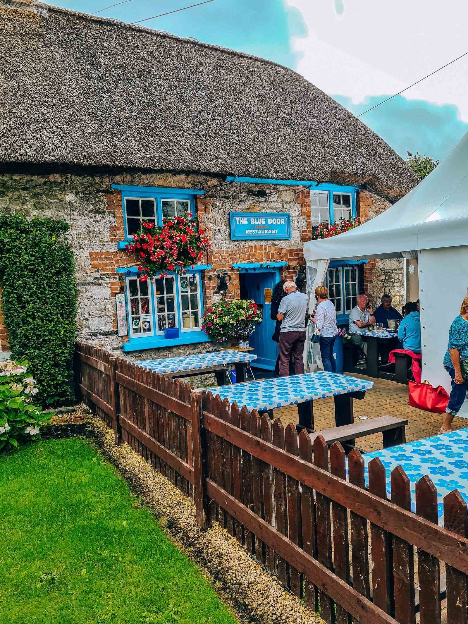  Thatched restaurant with blue door and outside seating 