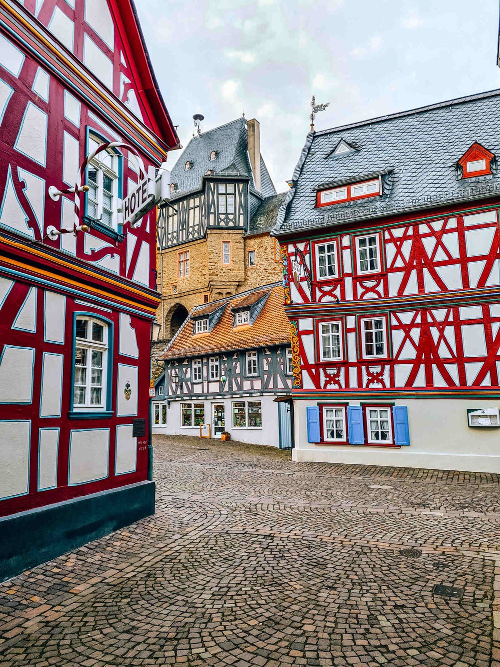  Cobbled street with many colourful traditional German buildings . 
