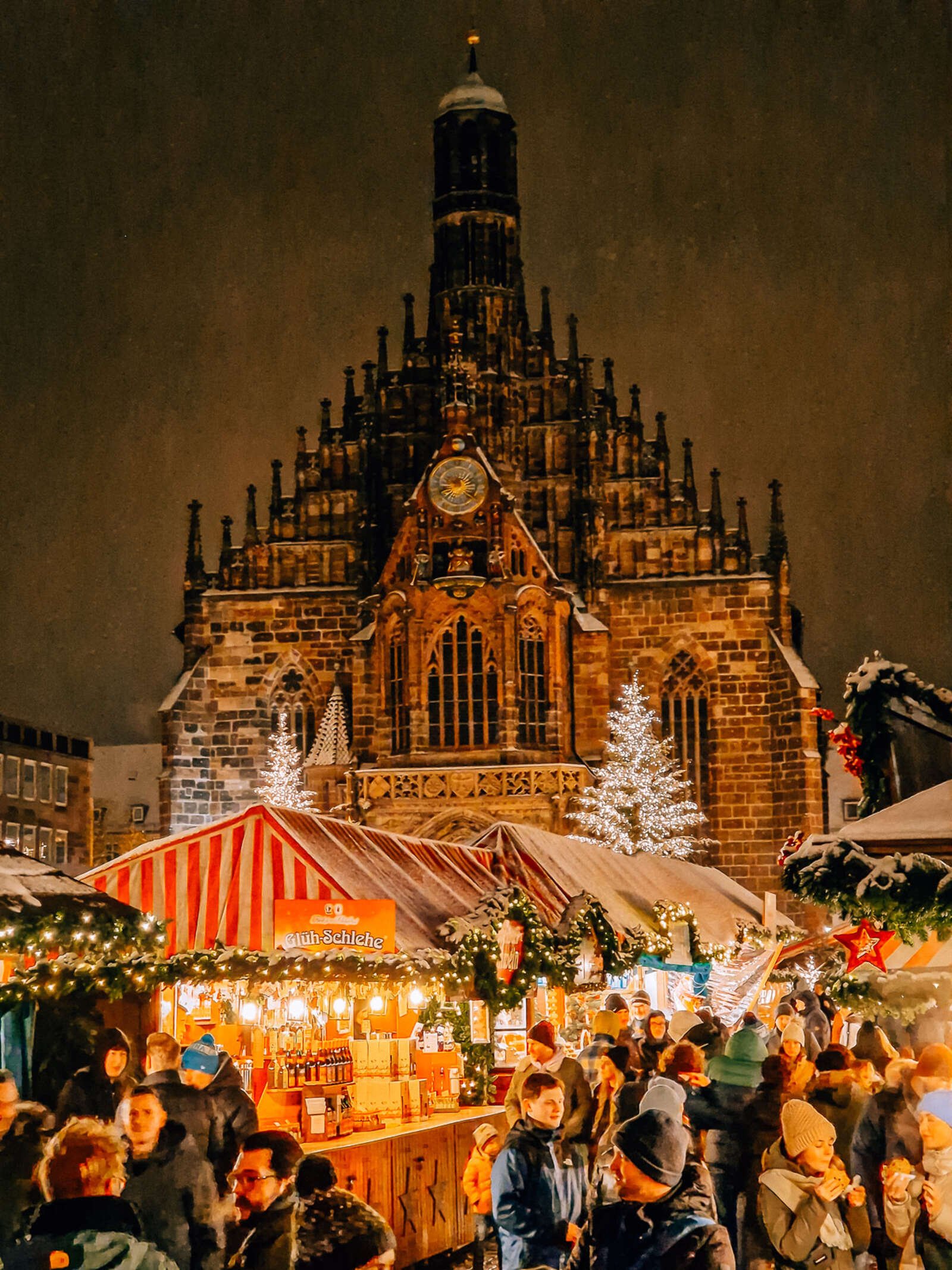 a gothic church in nuremberg towering over the chirstmas market at night
