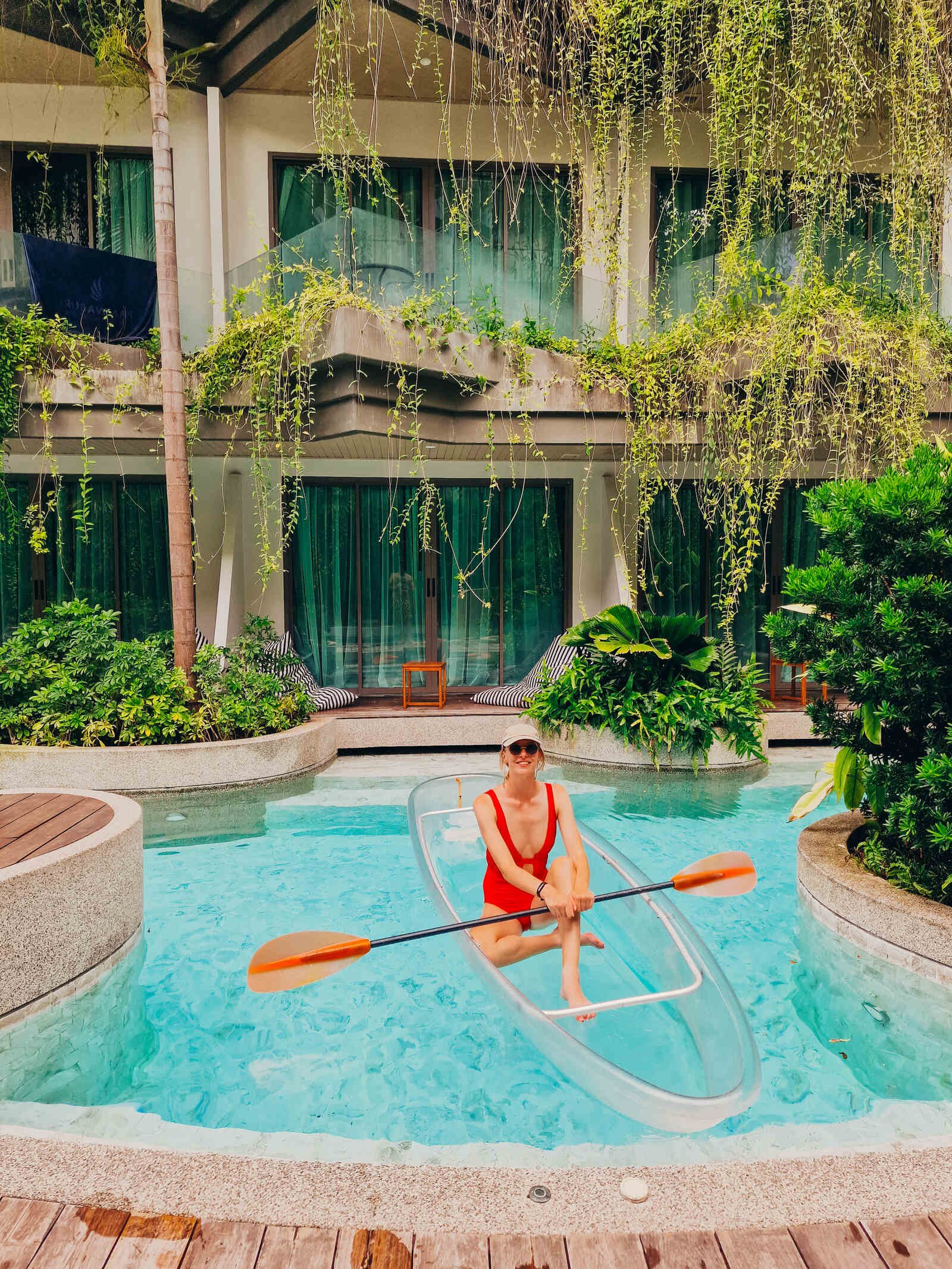 Helena in a glass bottom canoe in a pool with hotel rooms behind