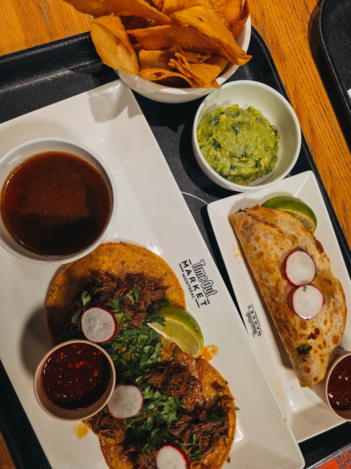 tacos, nachos and guac on a square plate that says "timeout market montreal"