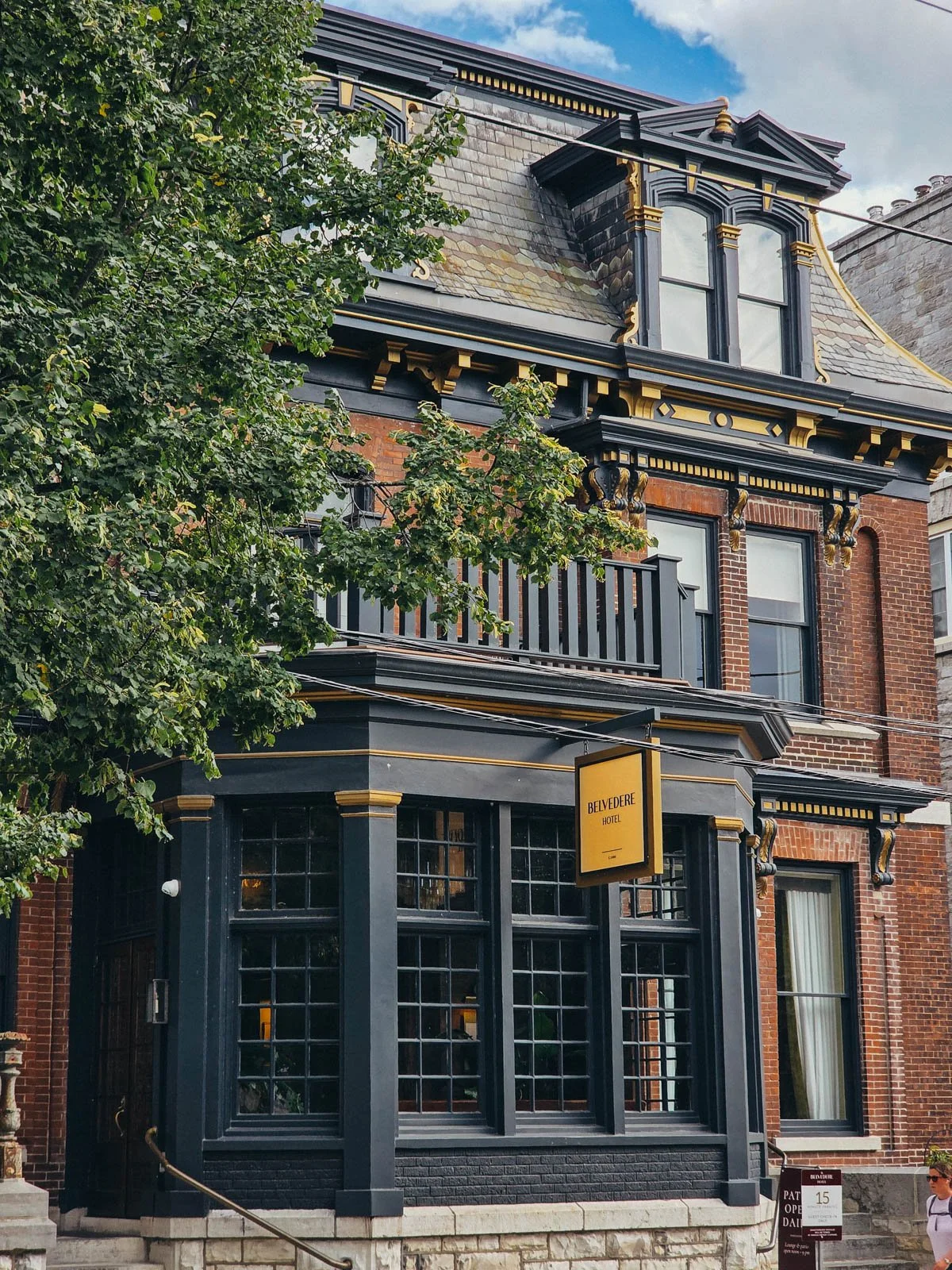 A large ornate brick house which has been converted into a hotel with black and gold window fixtures