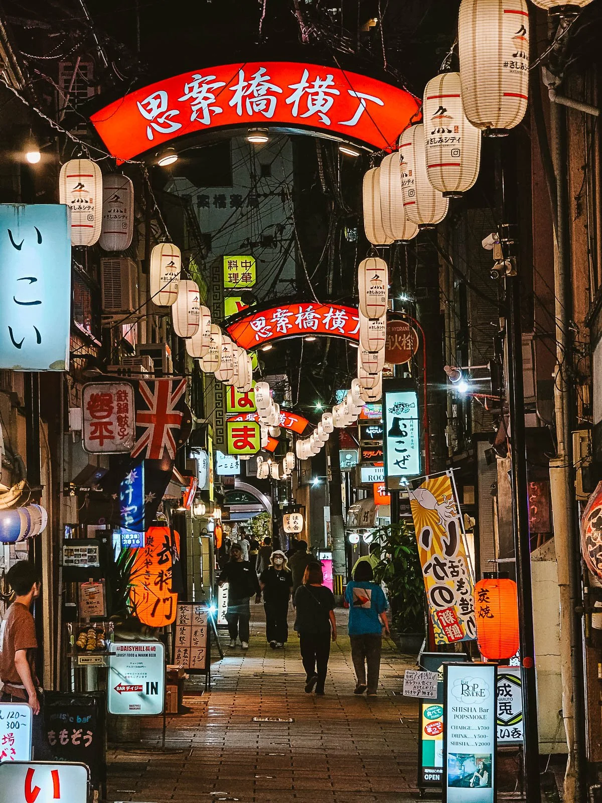 A street at night in Nagasaki filled with colourful lit up signs and lanterns