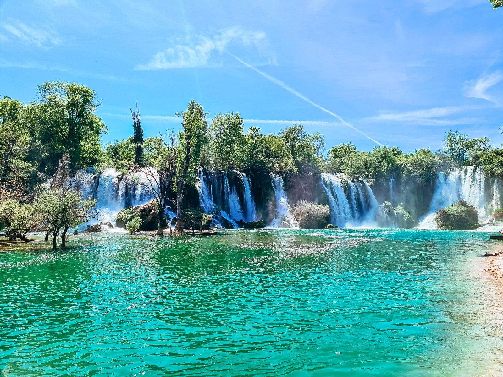 turquoise water in a lagoon with cascading waterfalls all around and blue sky