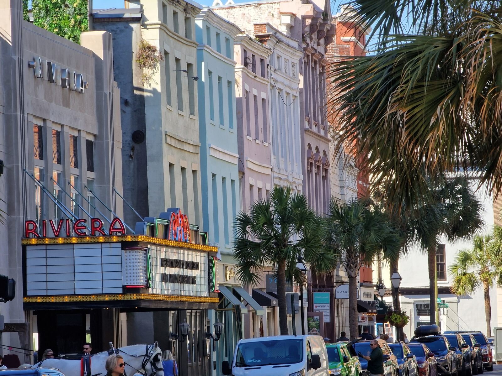 pastel coloured buildings with a vintage style theatre and palm trees lining the street