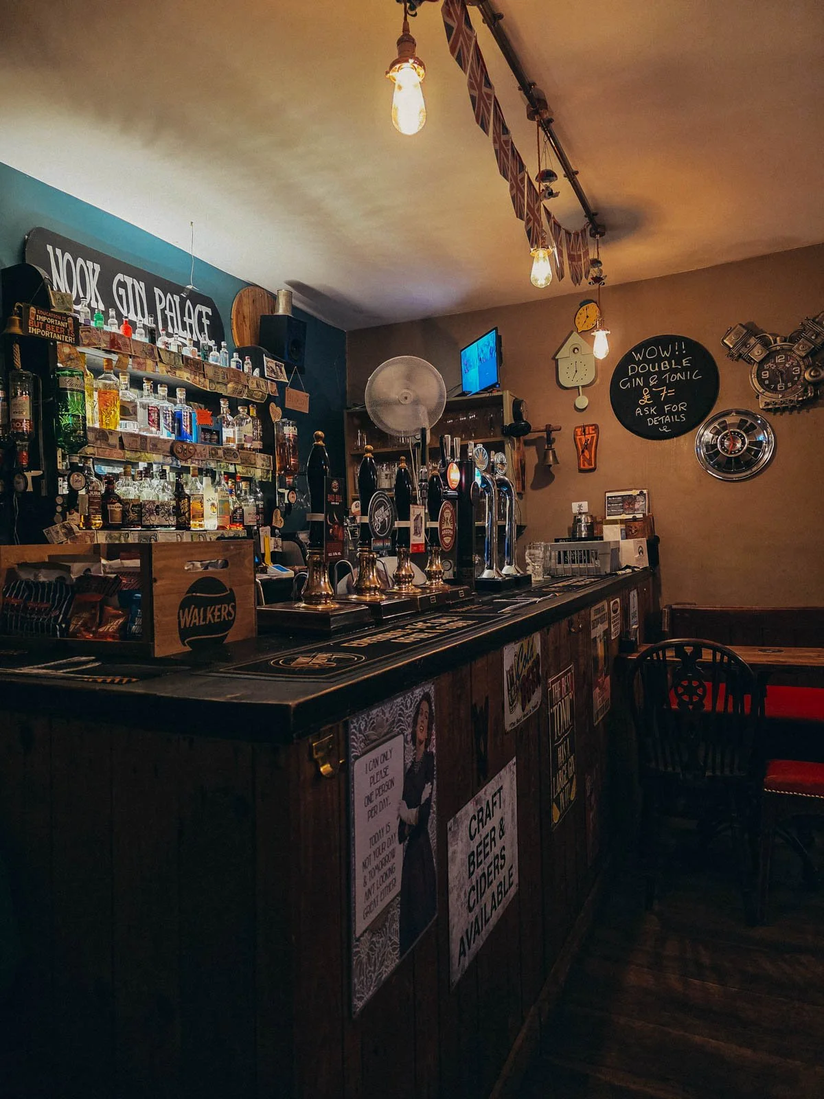 A small bar inside a warmly lit taproom with several beer taps  and drinks on offer behind the bar