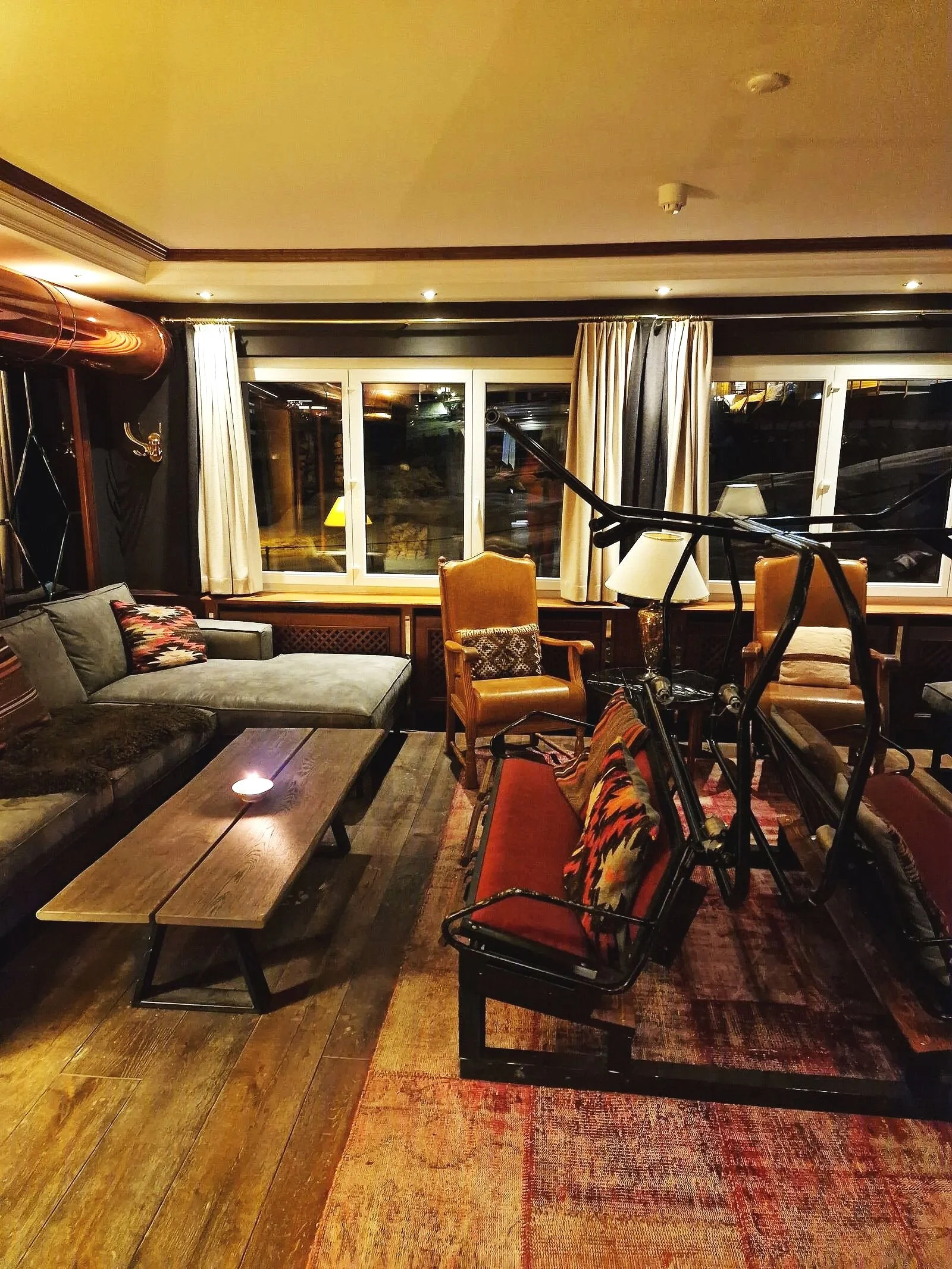 a cosy seating area with mismatched chairs, wooden floors, a wooden table and low warm lighting in a hotel bar