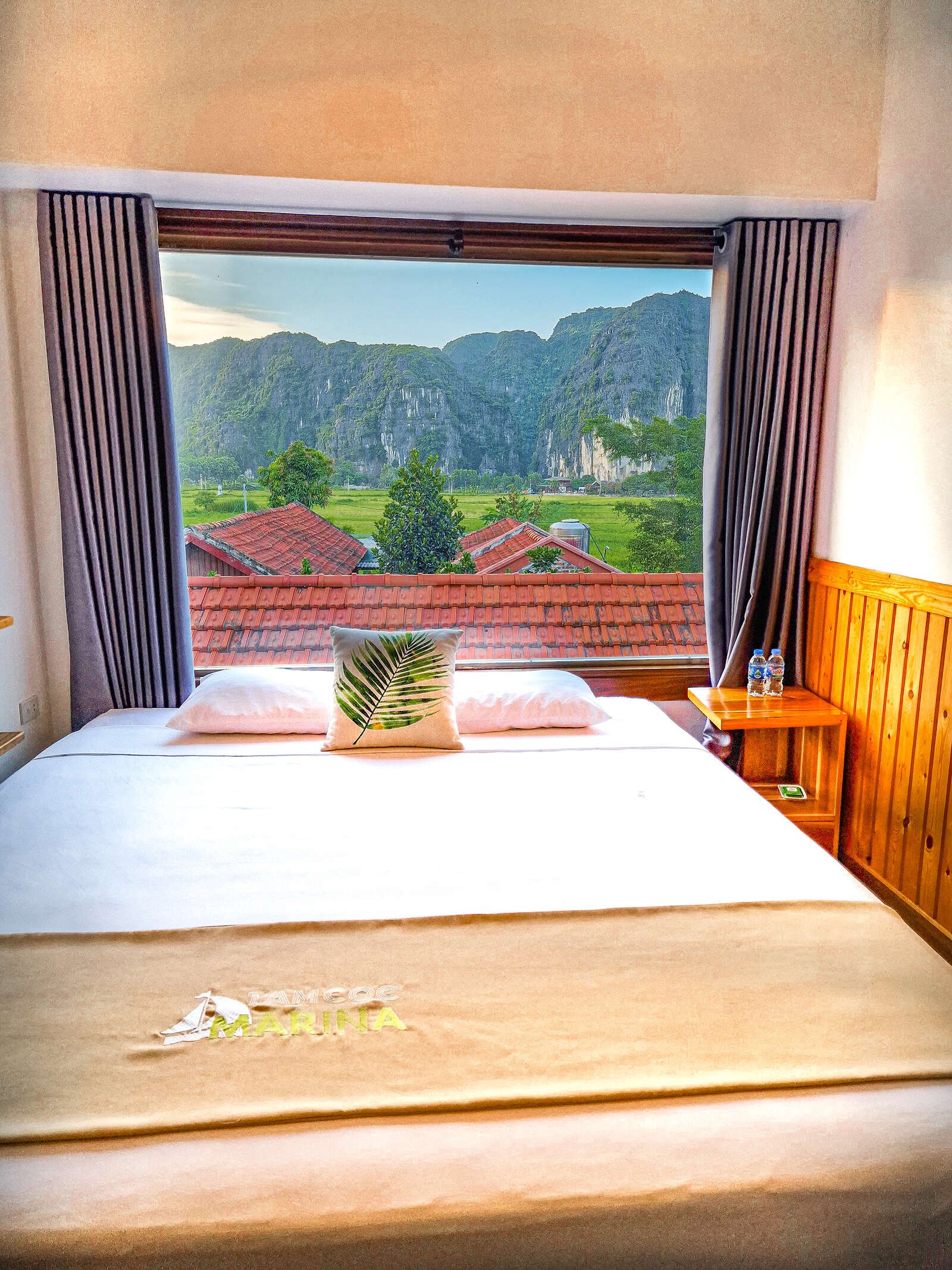 a bed in a hotel room below a window with a mountain view outside