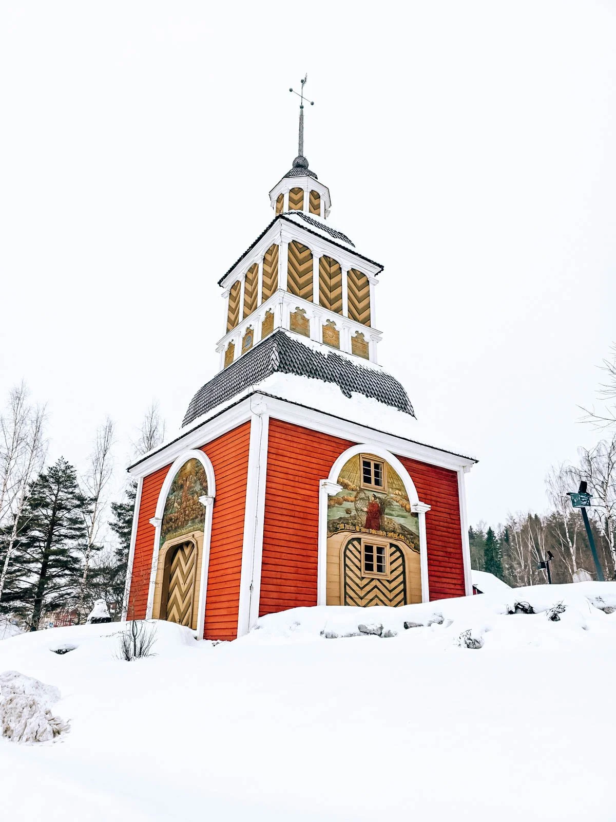 A tall red and yellow wooden square tower surrounded by snow