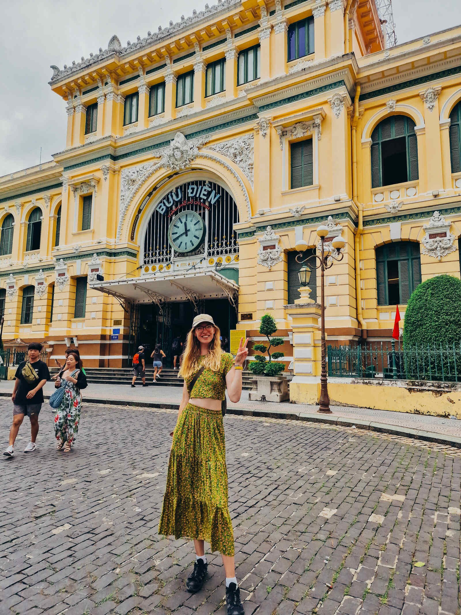 Helena standing in front of a yellow post office in Ho Chi Minh City