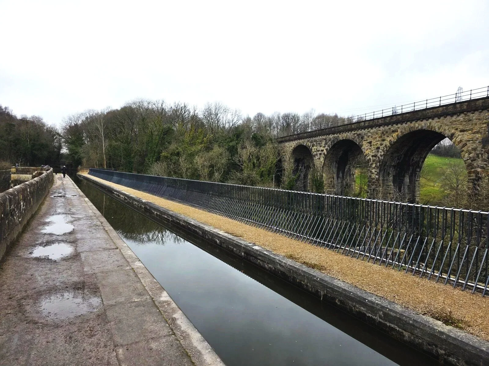 an aqueduct with water flowing across it in Marple and a train viaduct bridge behind