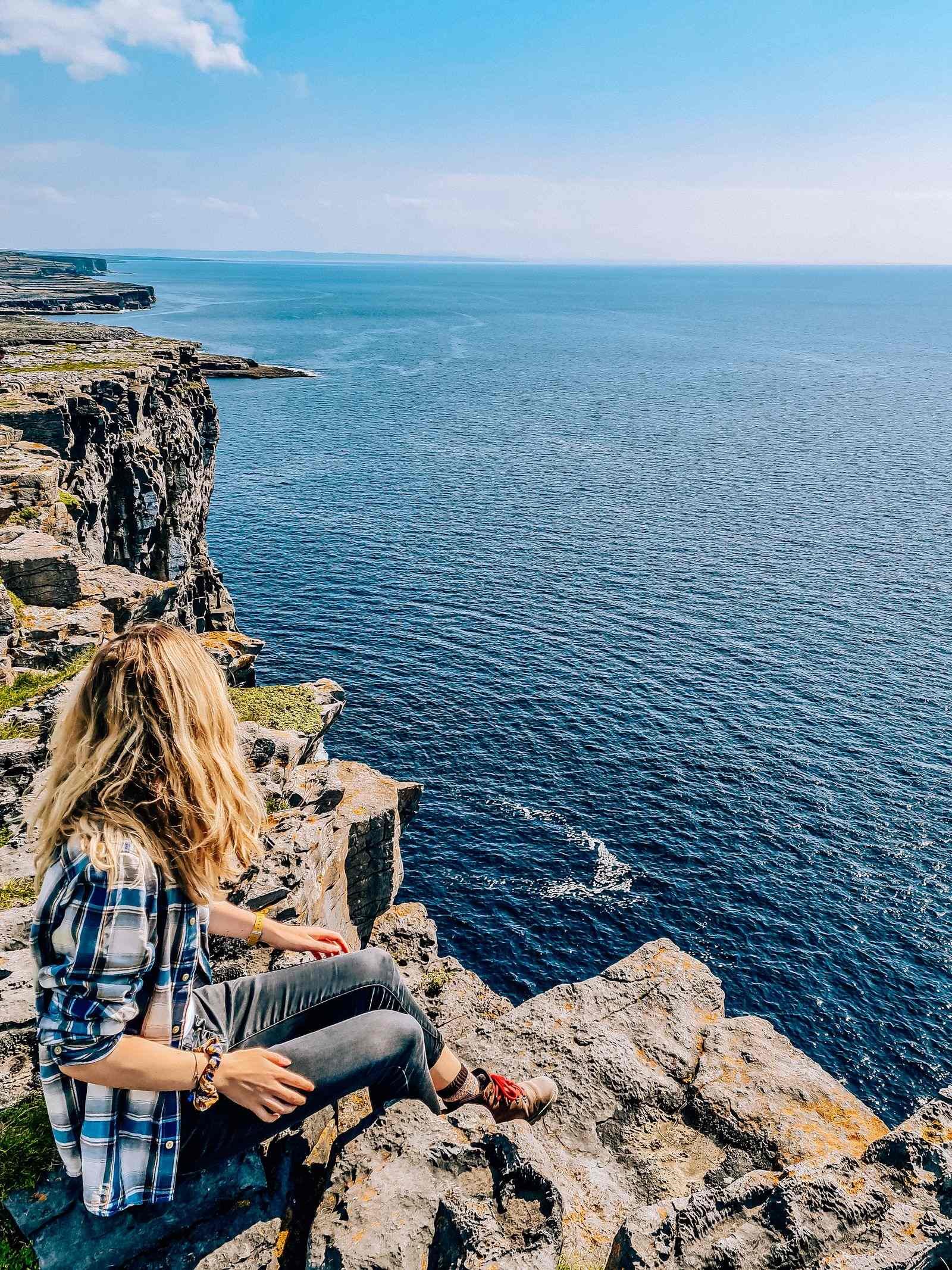 girl sitting on Inis Mor cliffs