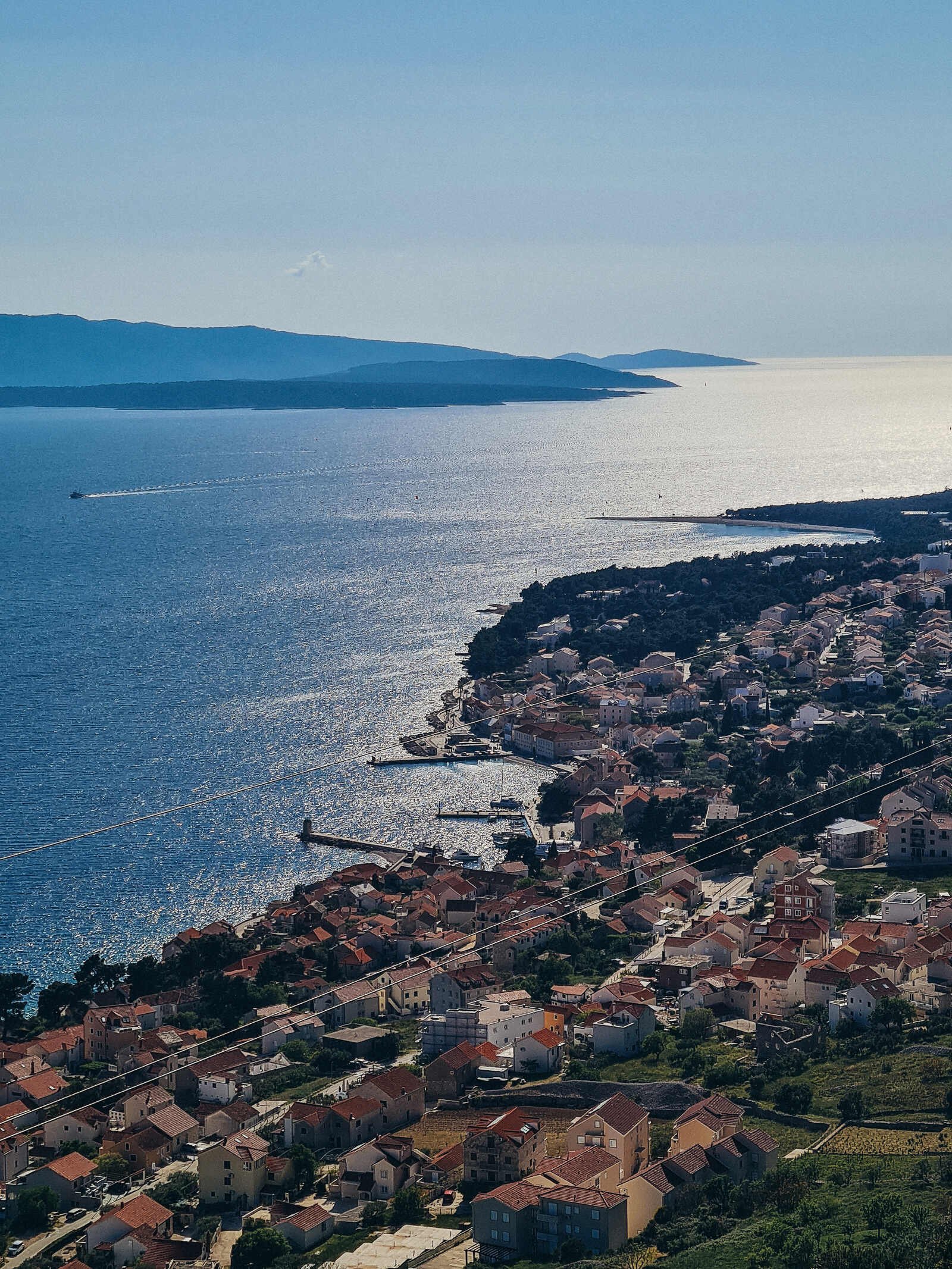 A view looking down on Bol town on the sea edge with other islands in the distance, view from the top of a mountain