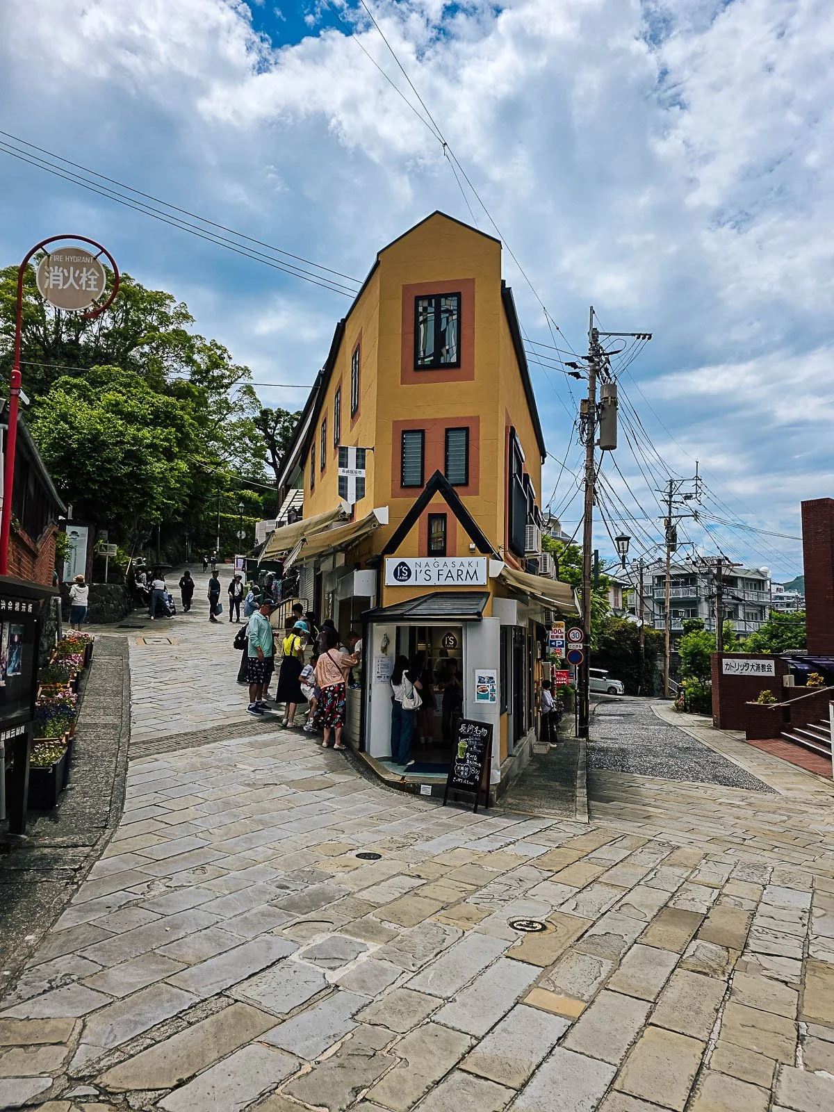 A narrow yellow building with a paved street leading up either side