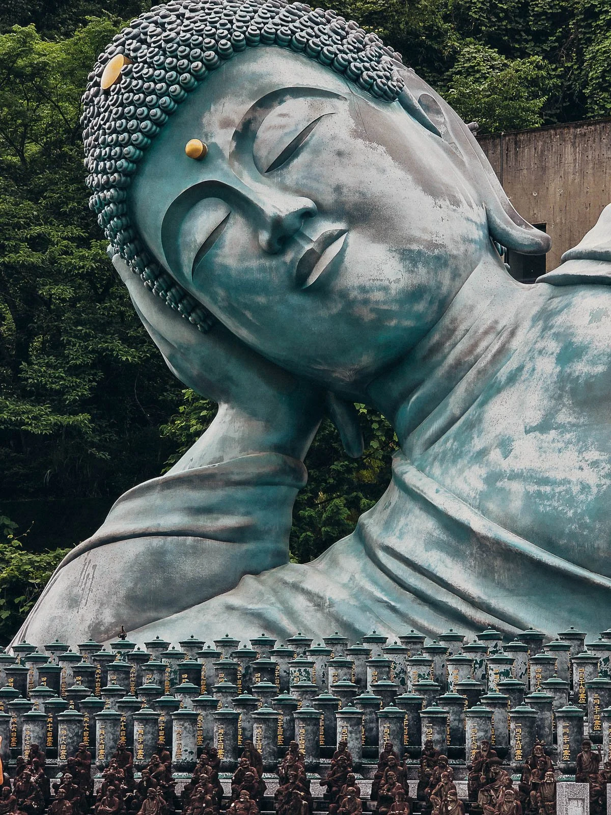 A large reclining Buddha stature with many little stoner statures on the steps in front of the Buddha