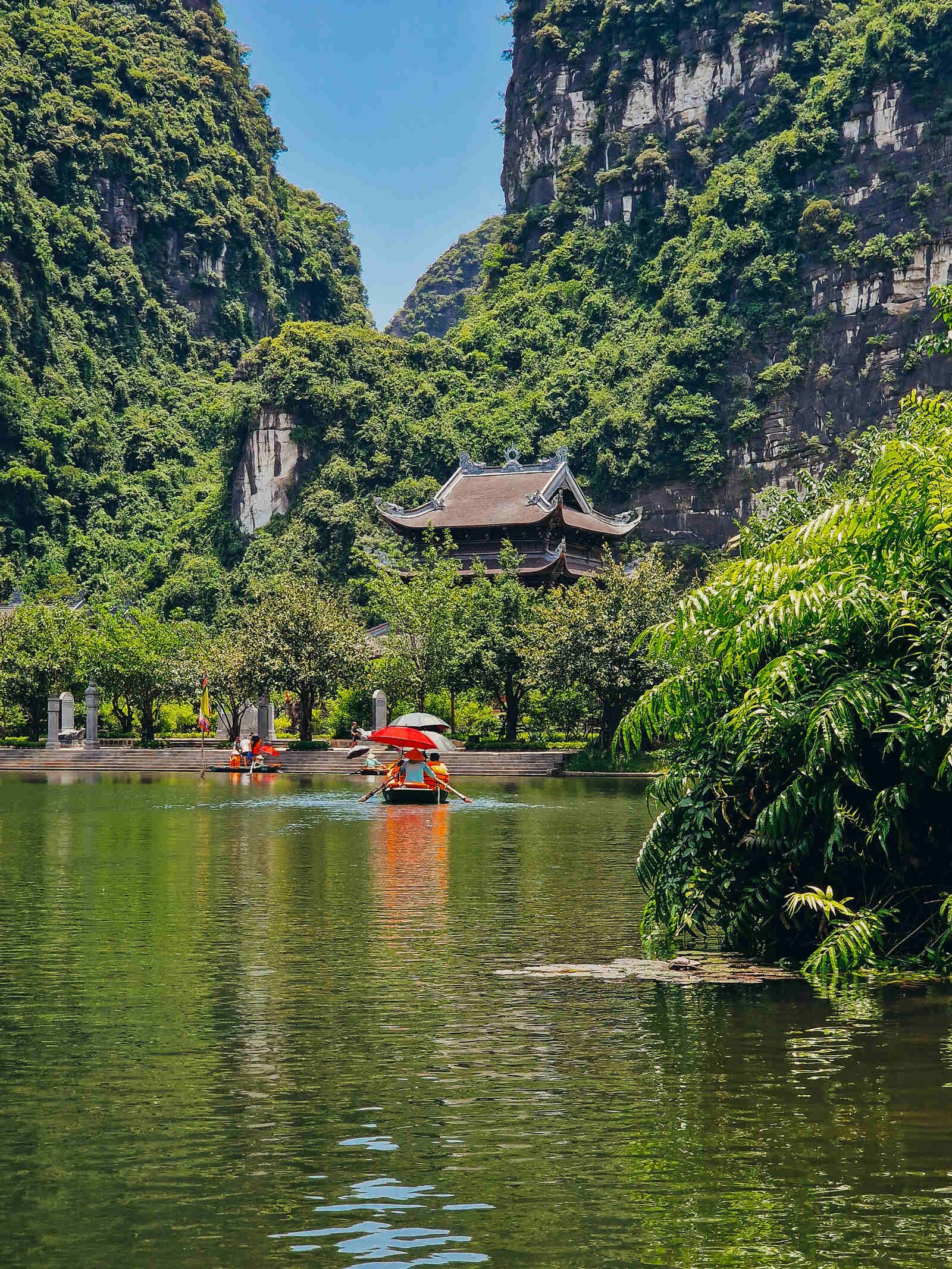 small rowing boats cruising down a waterway surrounded by green cliffs
