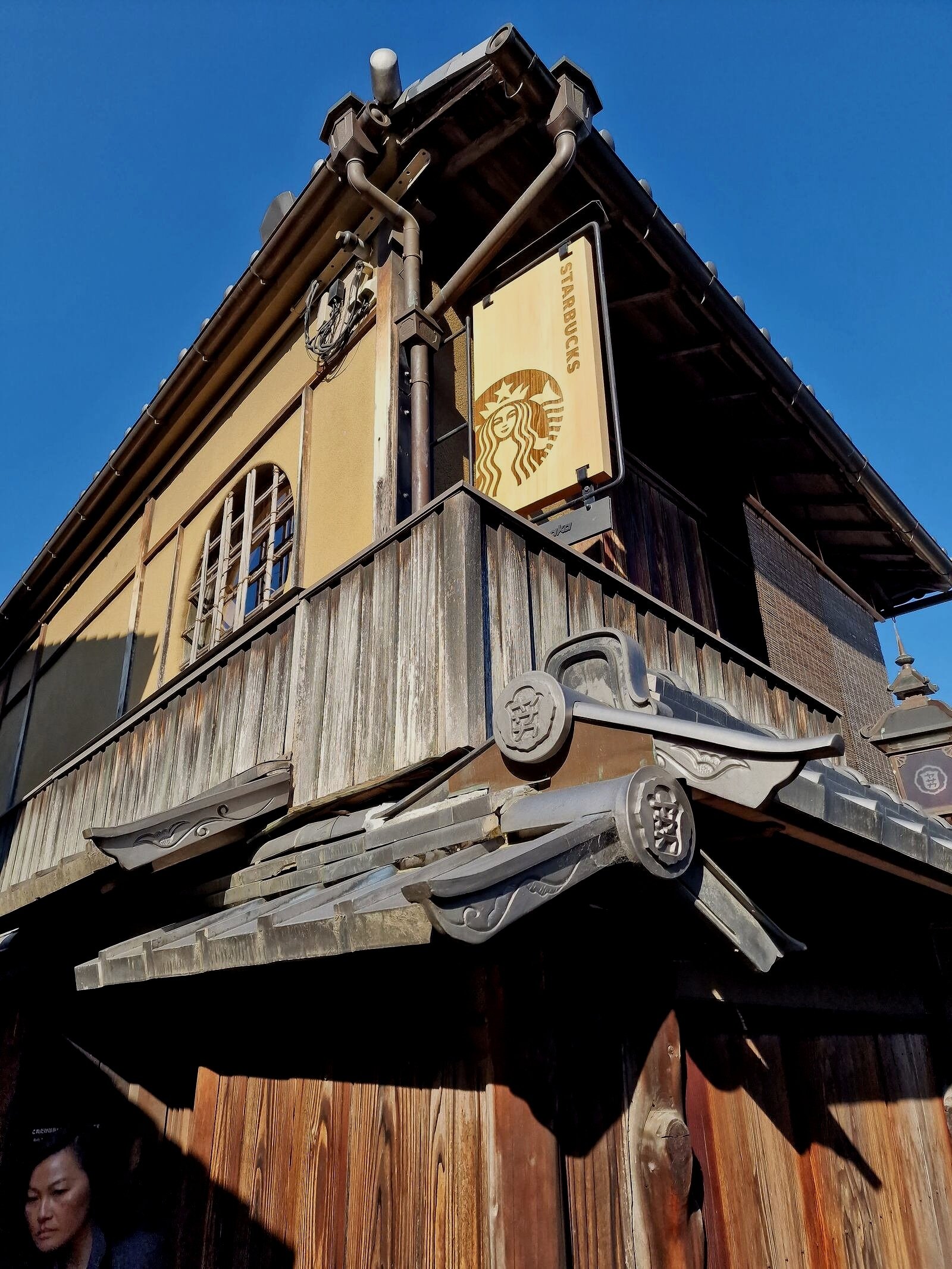 a traditional wooden Japanese house with the Starbucks logo on the side