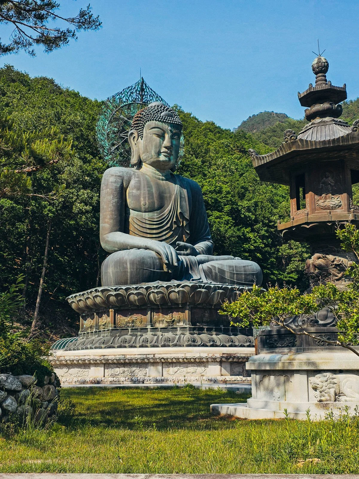 A large green buddha sitting on an elevated platform surrounded by trees in Seoraksan National Park, South Korea