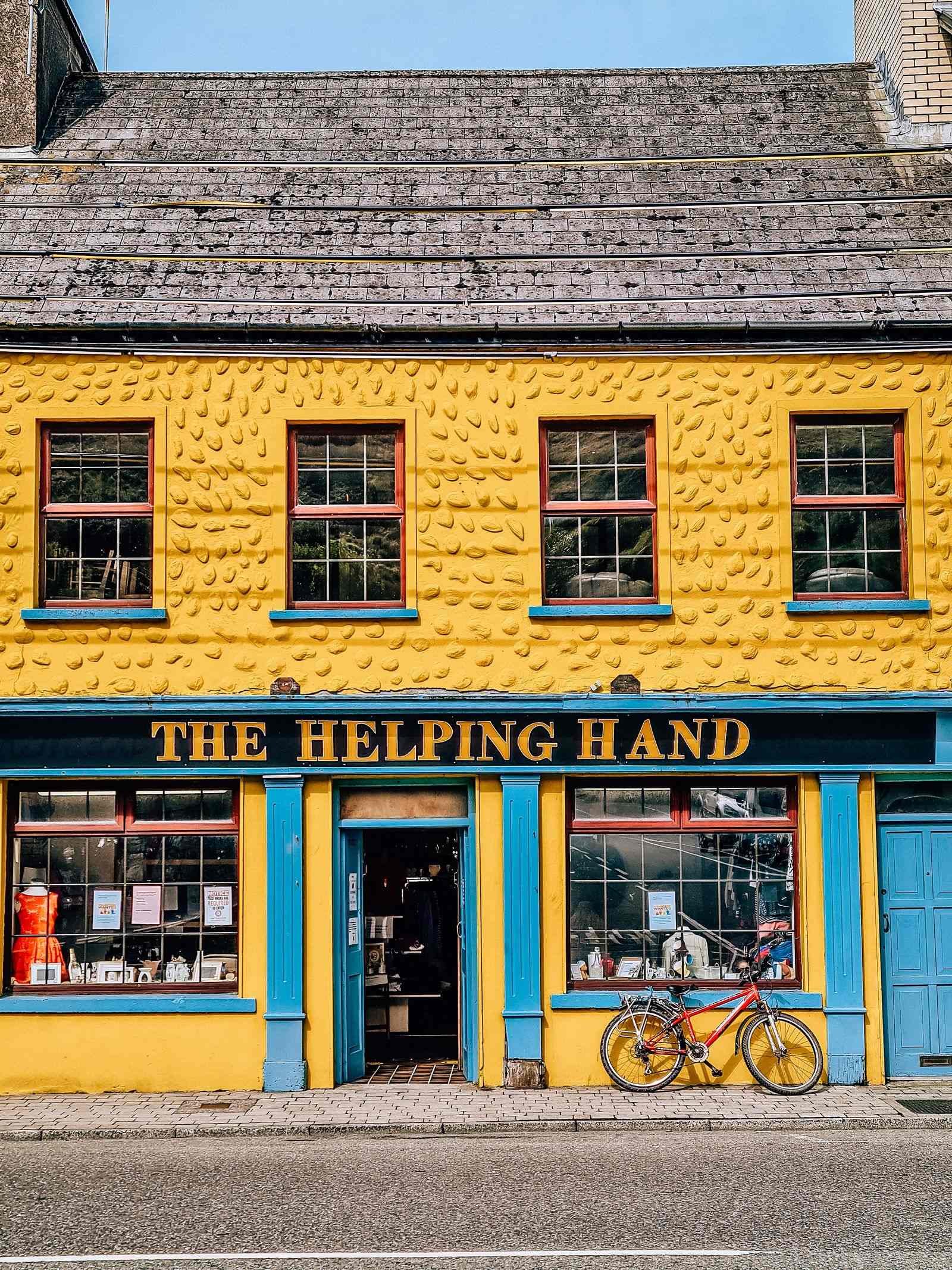 A colourful yellow shopfront with a red bike parked in front of it