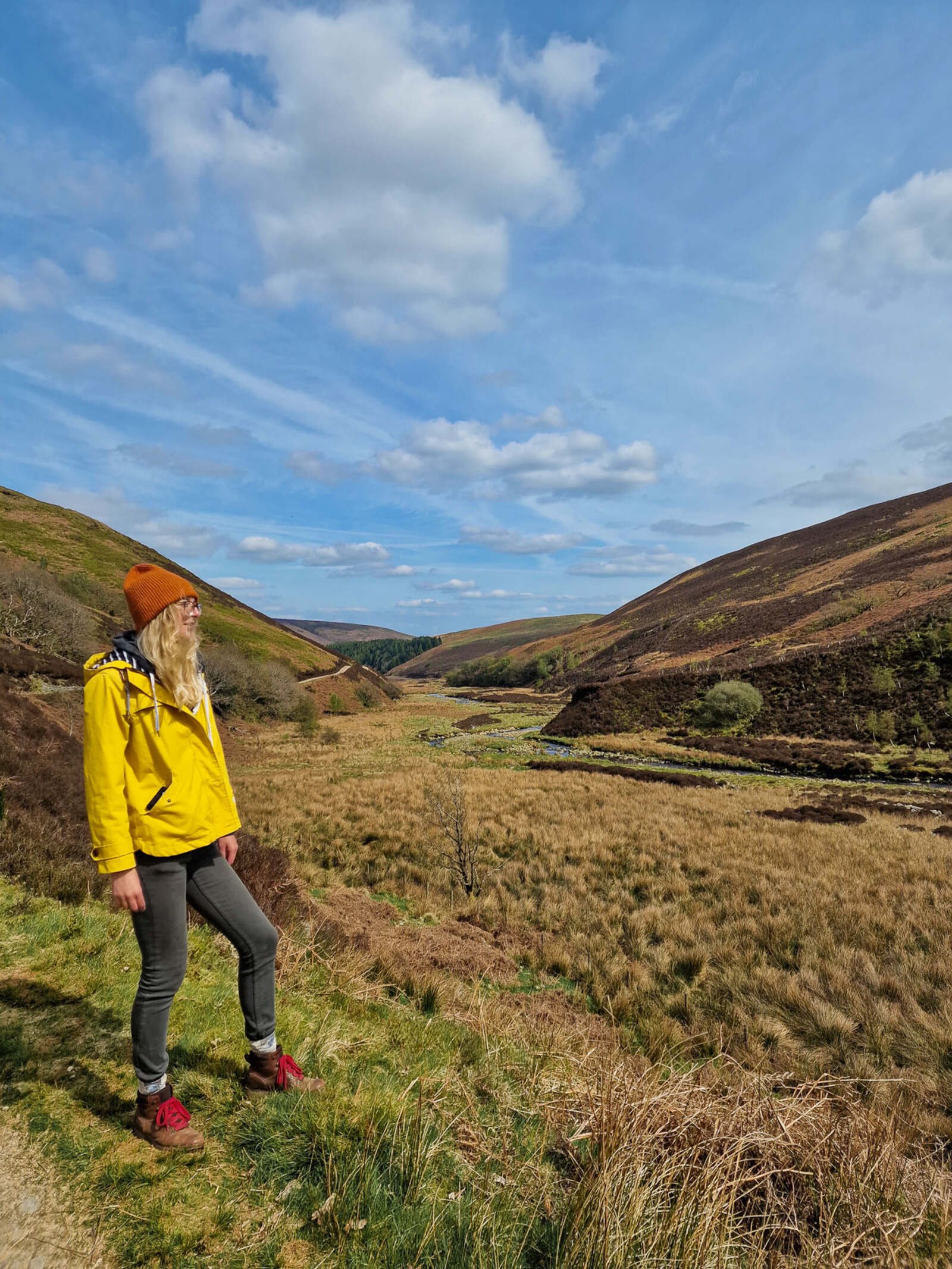 woman in yellow jacket looking out across a valley in Lancashire's forest of bowland