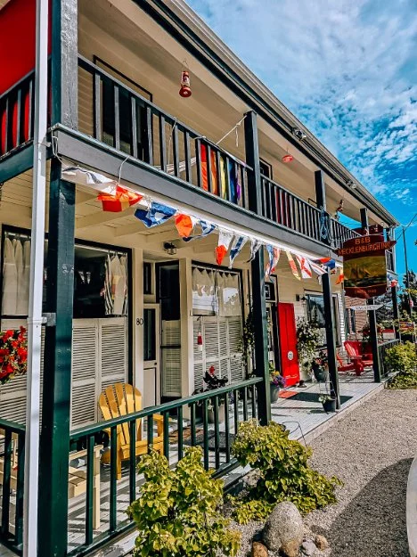 A two floor house with a porch and balcony with colourful bunting and a red door