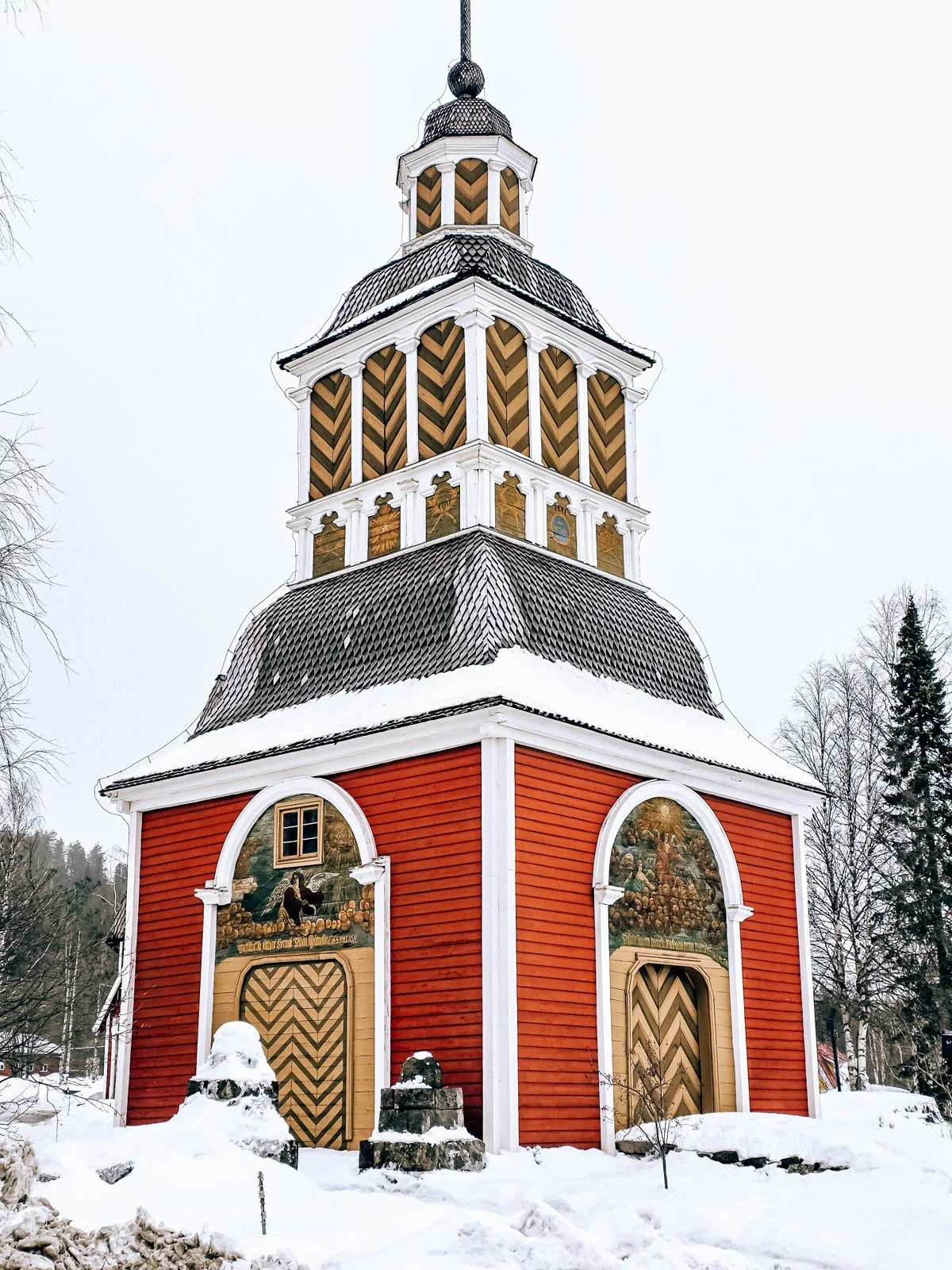 A large ornate wooden red tower surrounded by snow
