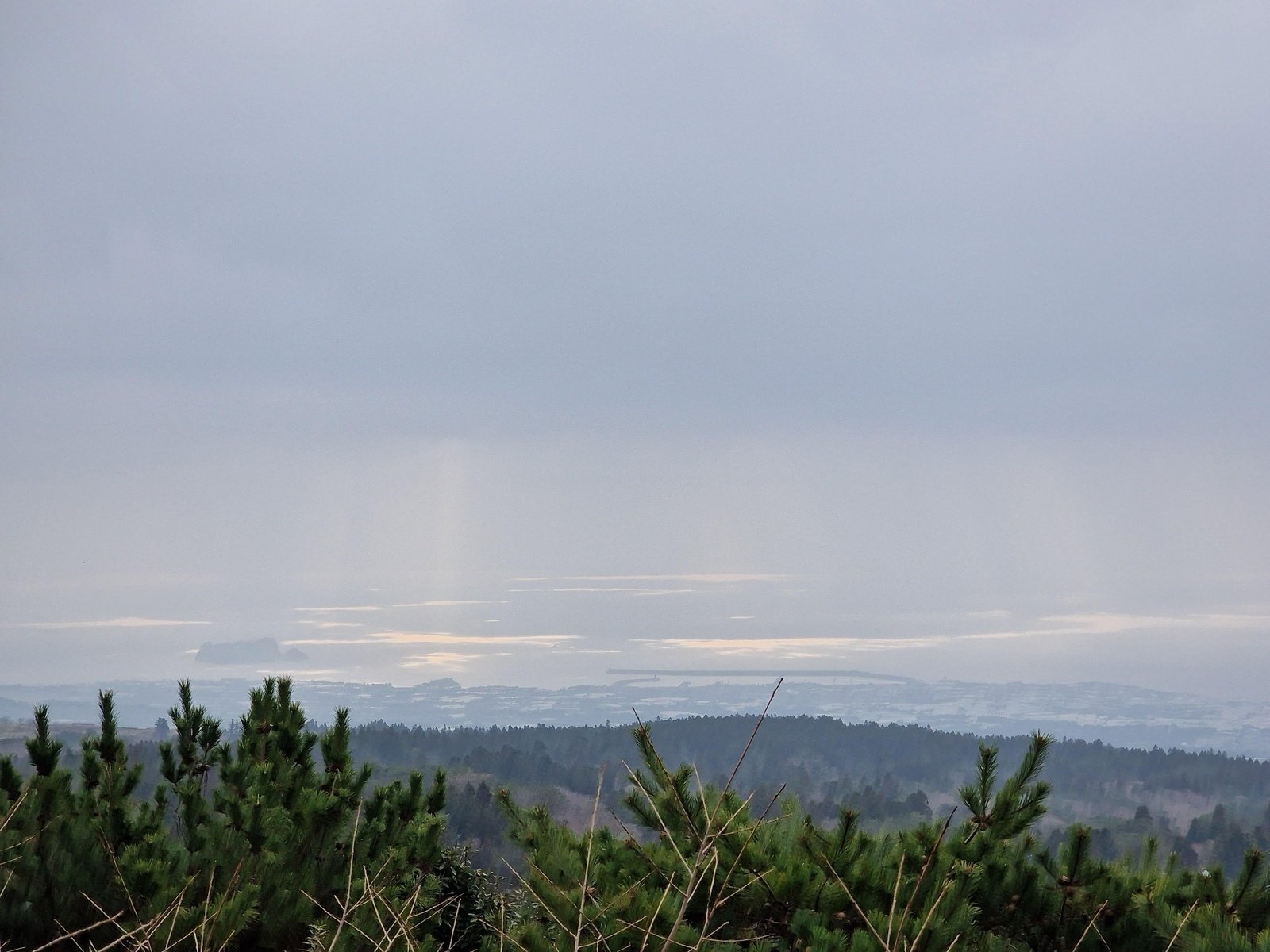 a landscape looking out across an island on a grey day with the sea visible in the distance