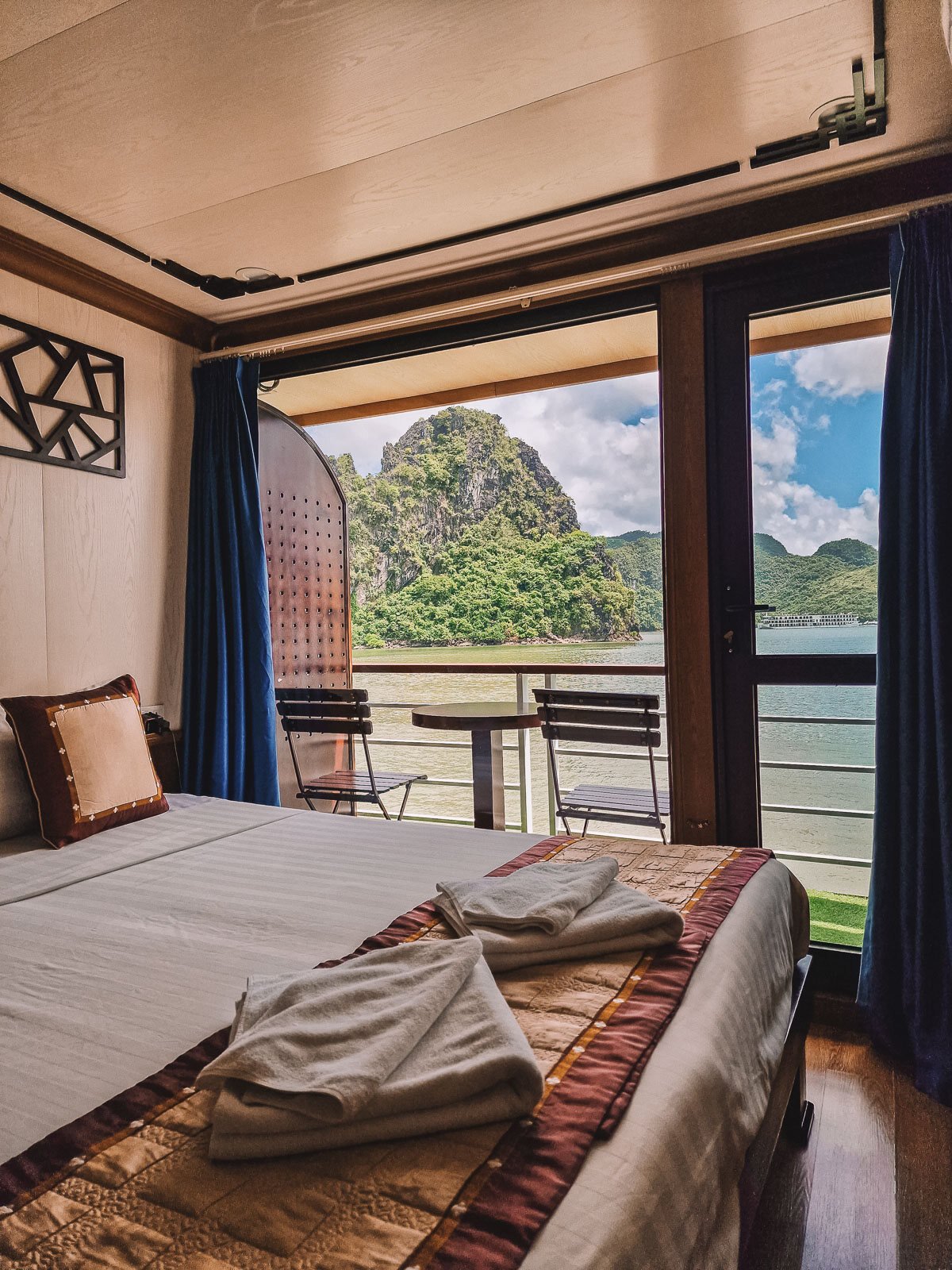 a cabin on a cruise ship with double bed and balcony with a view of ha long bay