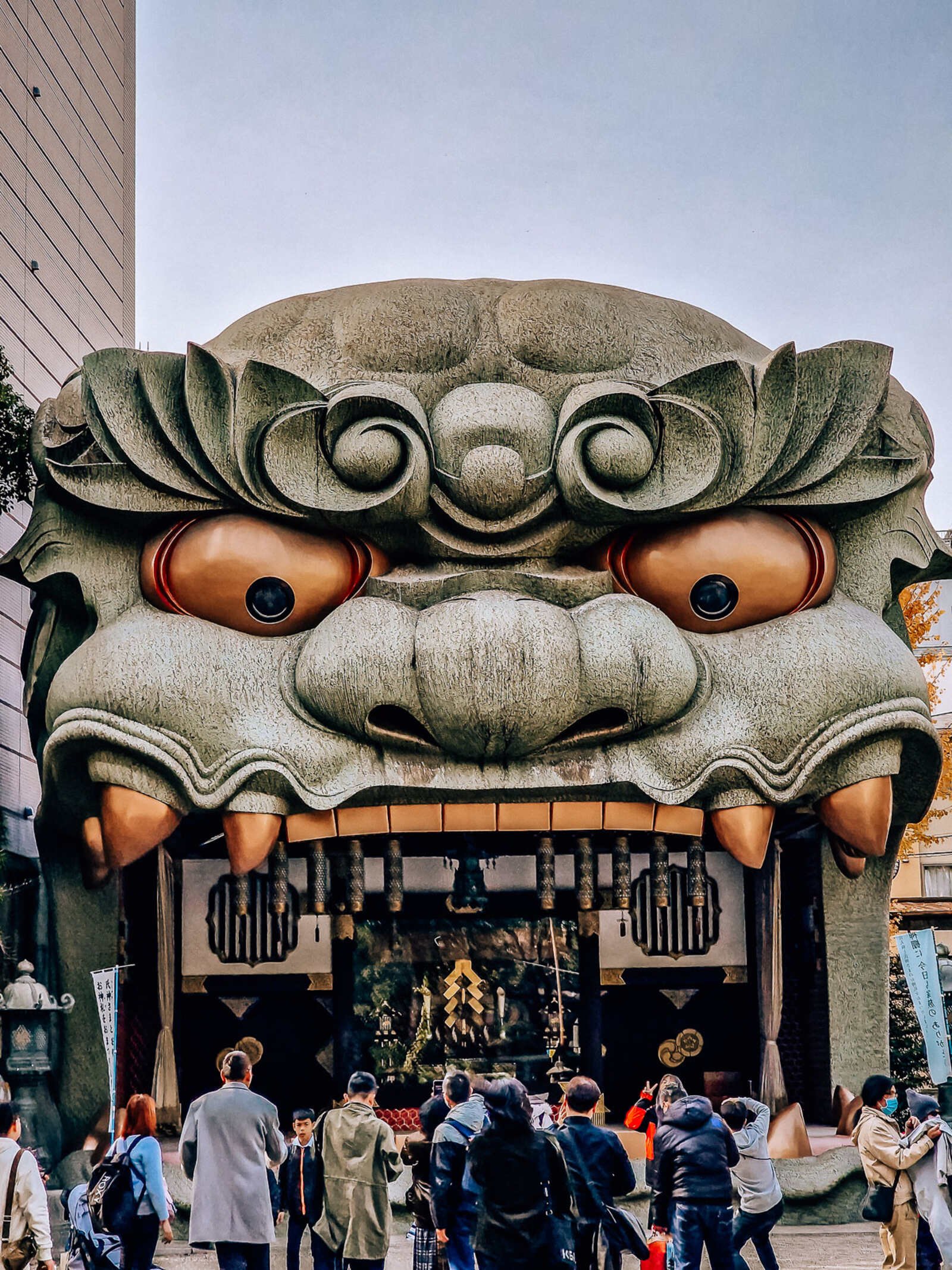 a huge stone dragon head at a shrine in osaka. It's teeth and eyes are gold and its mouth is open where a performance stage is inside