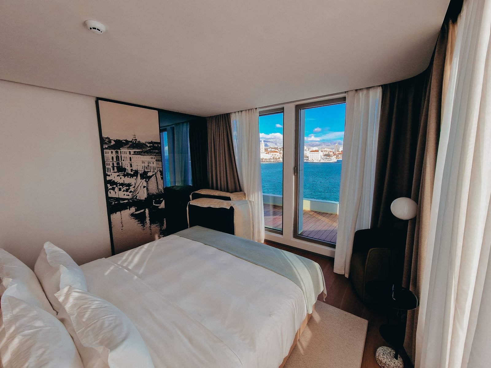 Inside a luxury boutique hotel in Split, a hotel room with views of the sea out of the doors and balcony