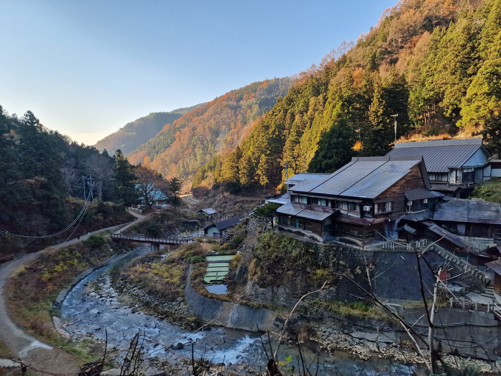 a river winding through a valley with a wooden guesthouse on the far bank