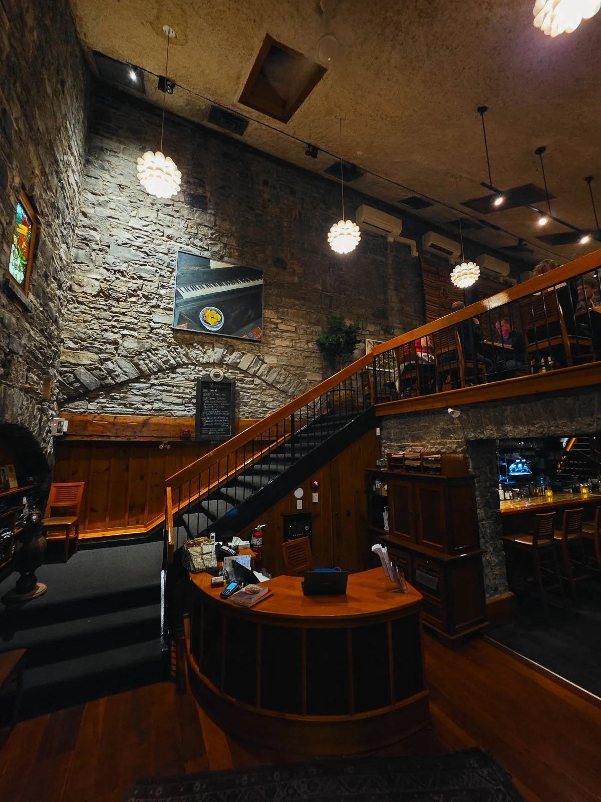 The large stone interior of a restaurant with a large staircase leading to the balcony second floor - a restaurant in Kingston Ontario