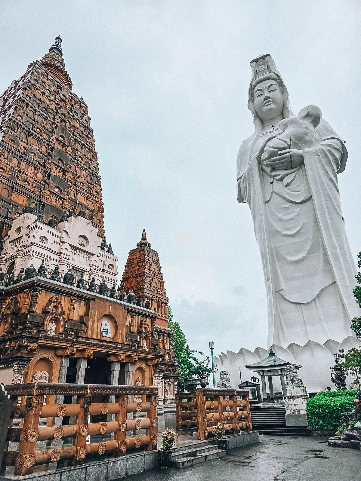 A large clay stone temple next to a huge statue of the Goddess of Mercy at a temple, one of the most unique places to visit in Kyushu