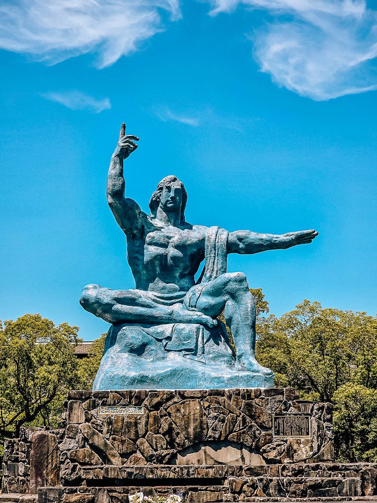 A large statue of a man in a posed position on top of a stone platform