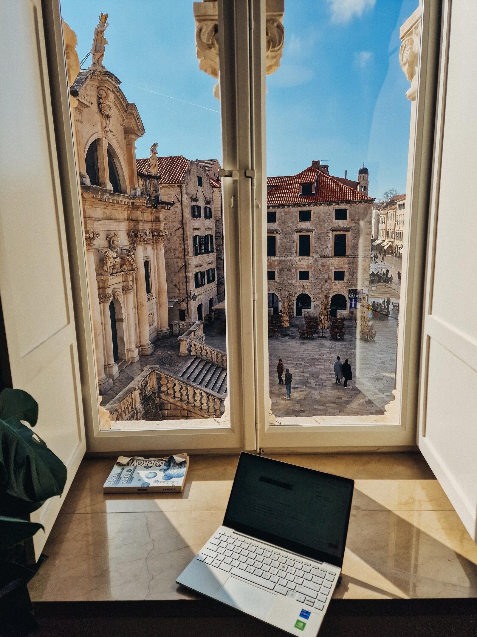 digital nomad in dubrovnik with a laptop working at a window with a view of dubrovnik old town