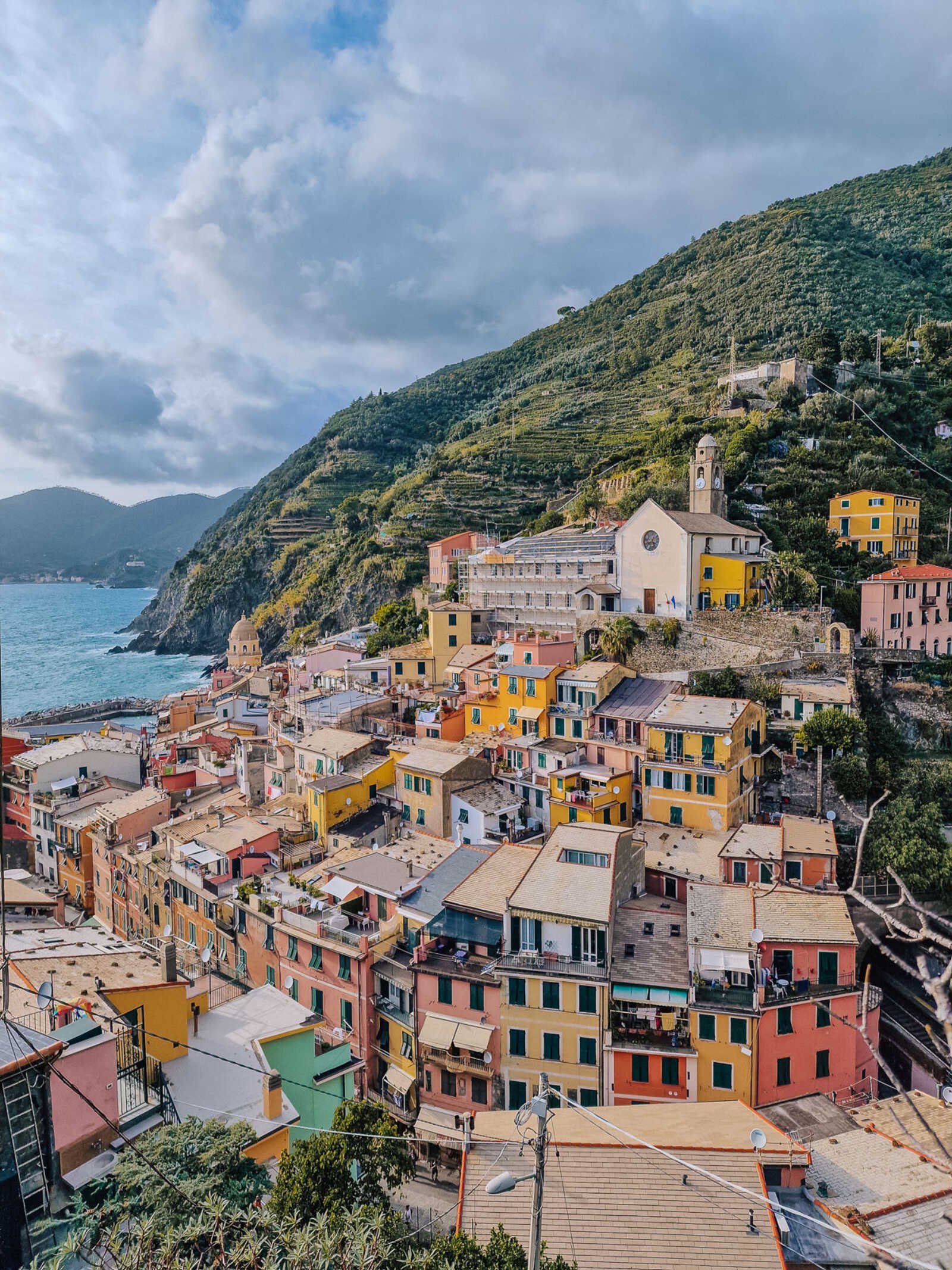 the colourful village of vernazza italy perched on a sea cliff with greenery behind