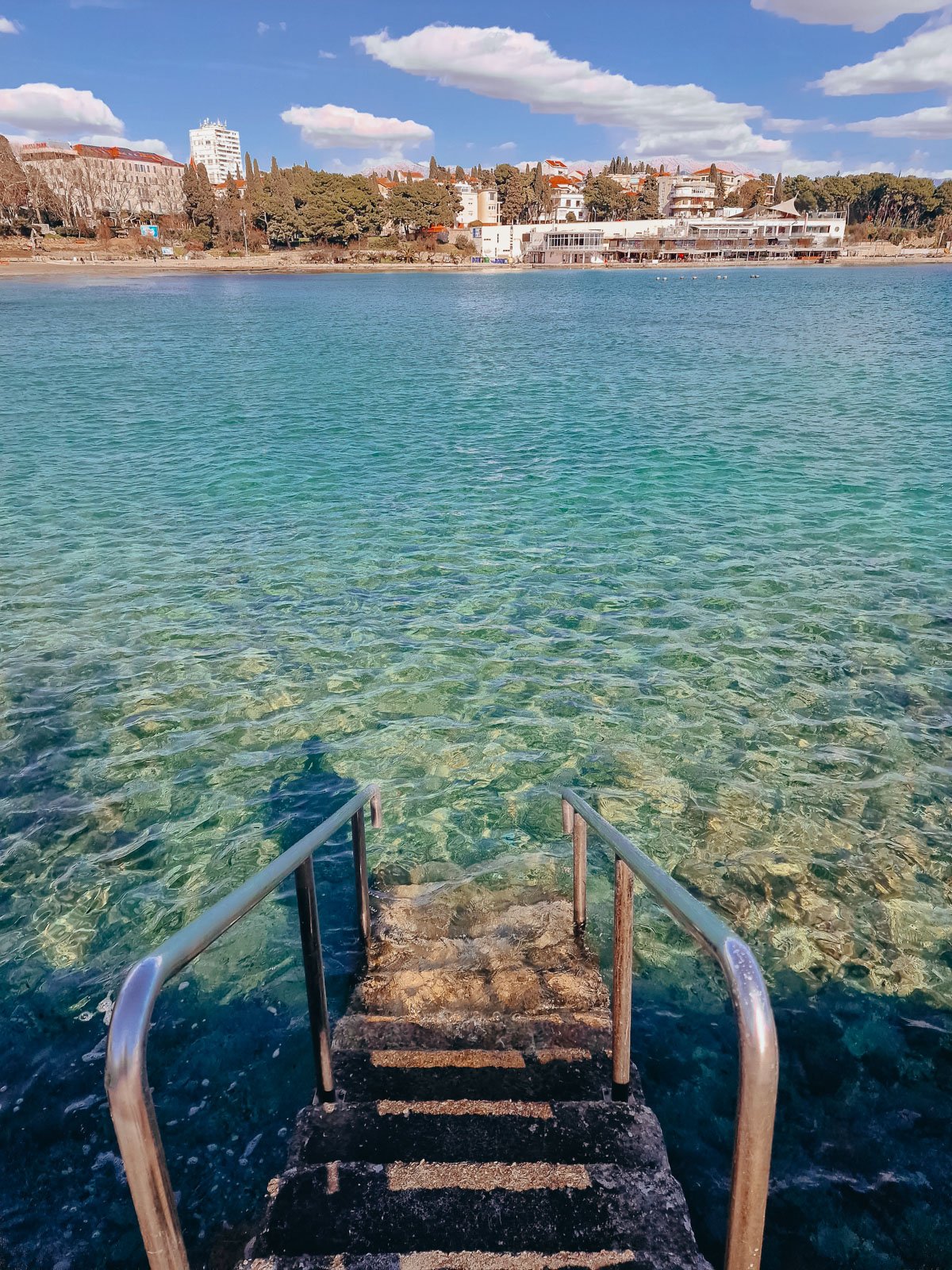 Metal steps into a calm turquoise blue bay of water