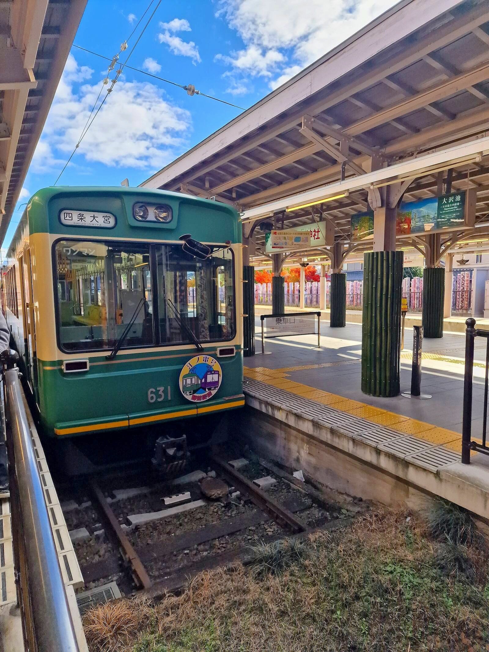 a flat-fronted train at the end of a line parked in a station, train is cream and green with a large window on the front