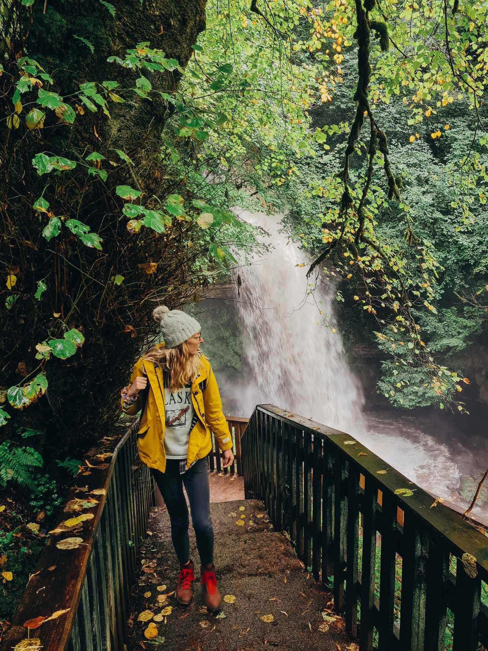 A lady in yellow on a walkway with a waterfall in the background