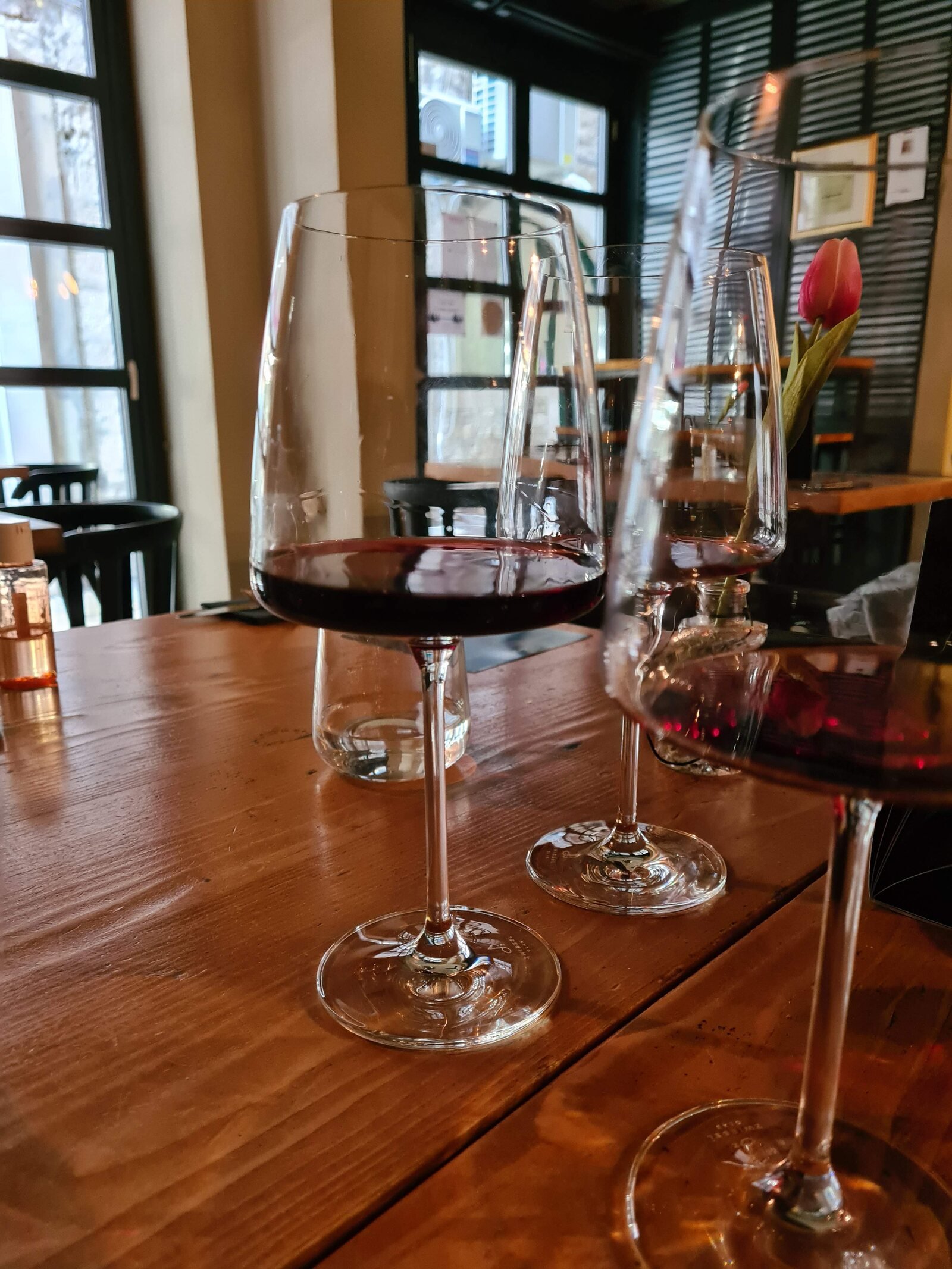Three glasses with tasting portions of red wine on a dark wooden table