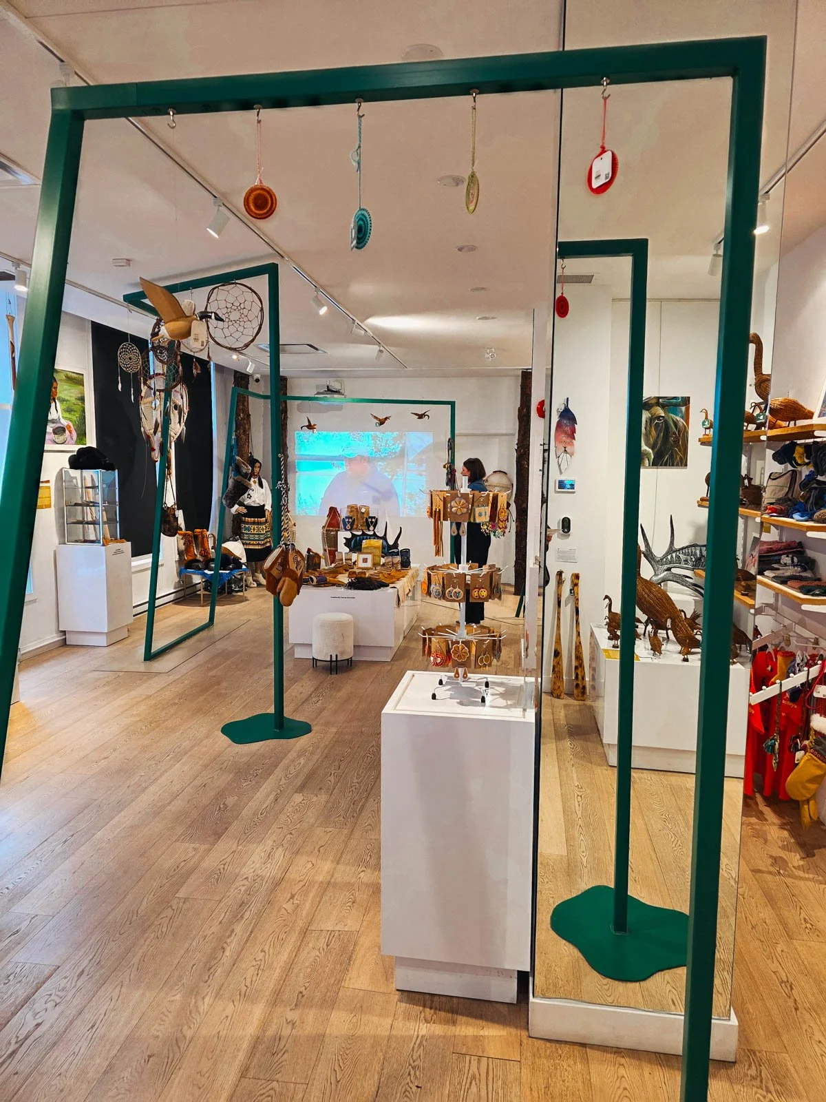 Inside a shop with wooden floor, green structures and lots of displays of indigenous crafts throughout the store