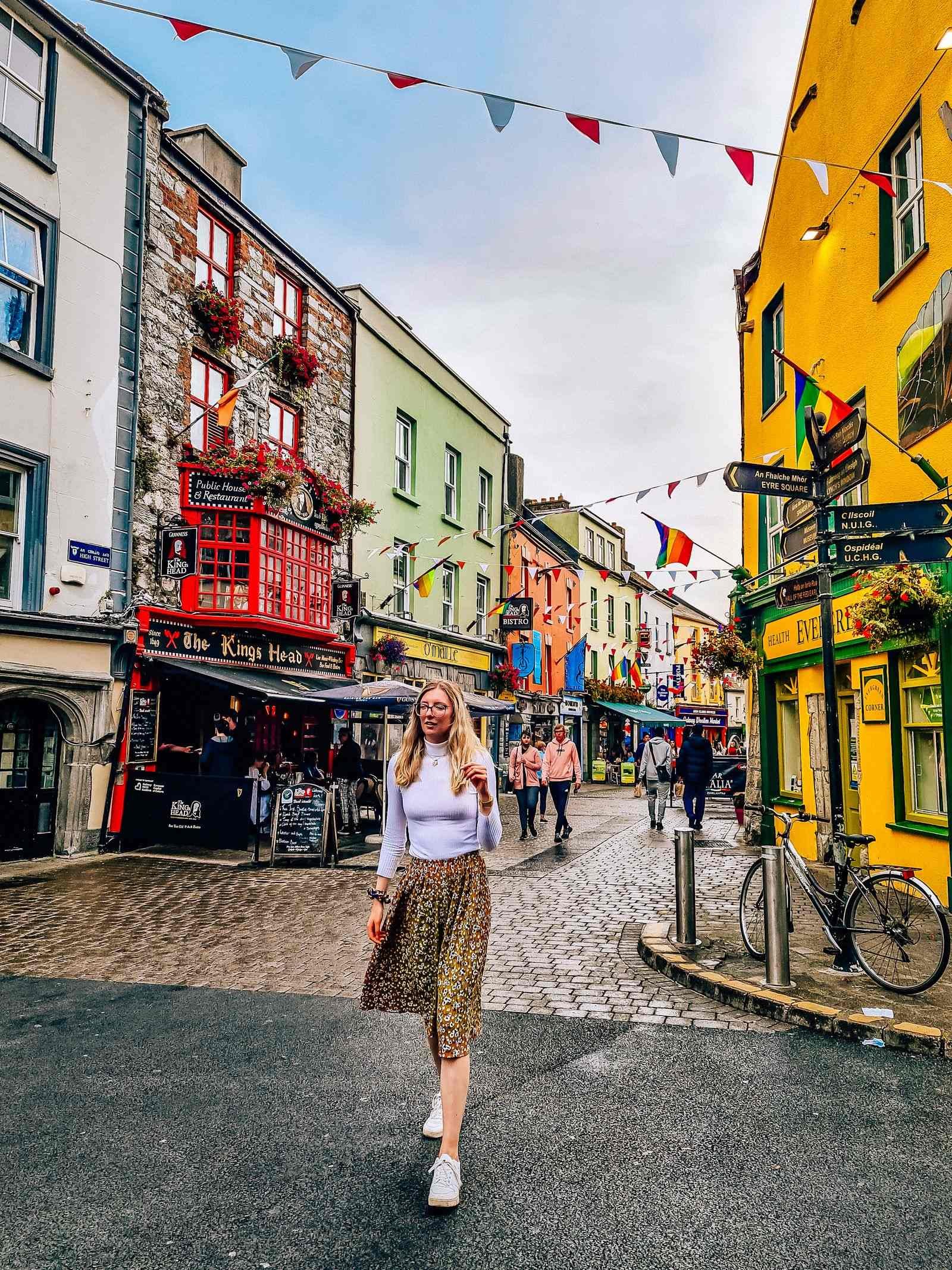 girl walking down colourful street in galway with bunting and yellow building