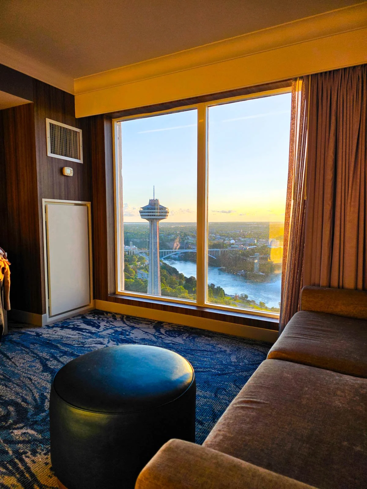A view form a hotel window looking out at a river and bridge with a tall tower at sunset