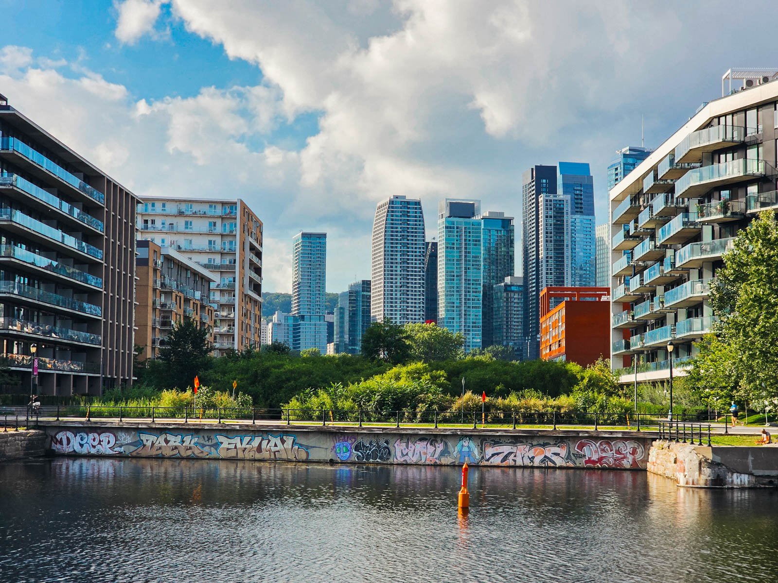Looking across a canal to modern glass buildings and skyline on the far side