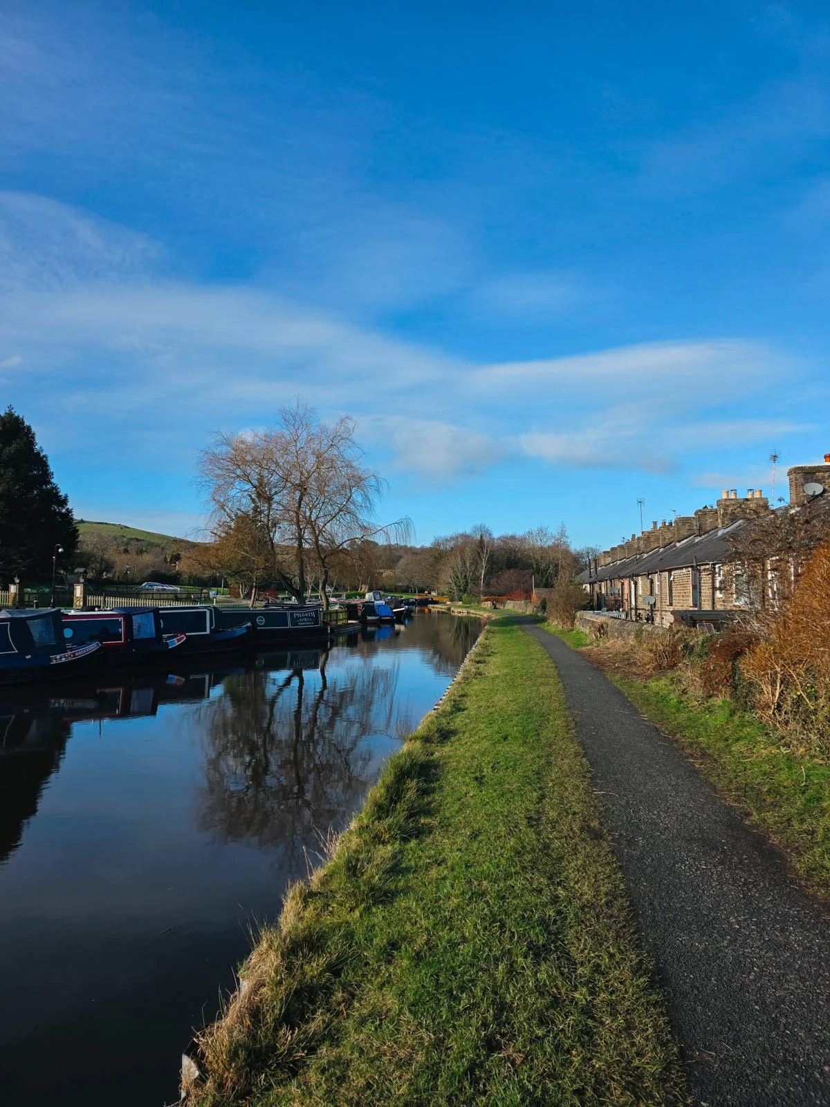 A canal marina with many narrowboats on the left and a canal walking path on the right - the Peak Forest canal is an easy Peak District walk
