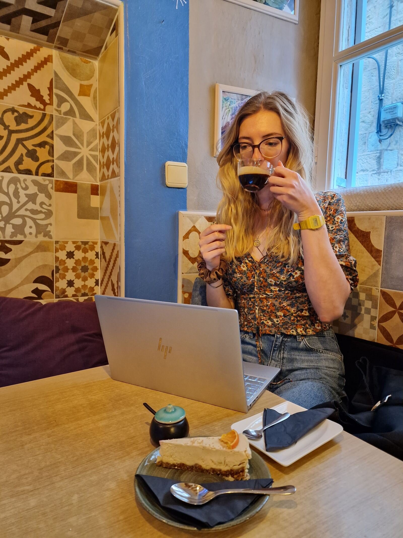 girl sipping coffee at a table with a laptop on it