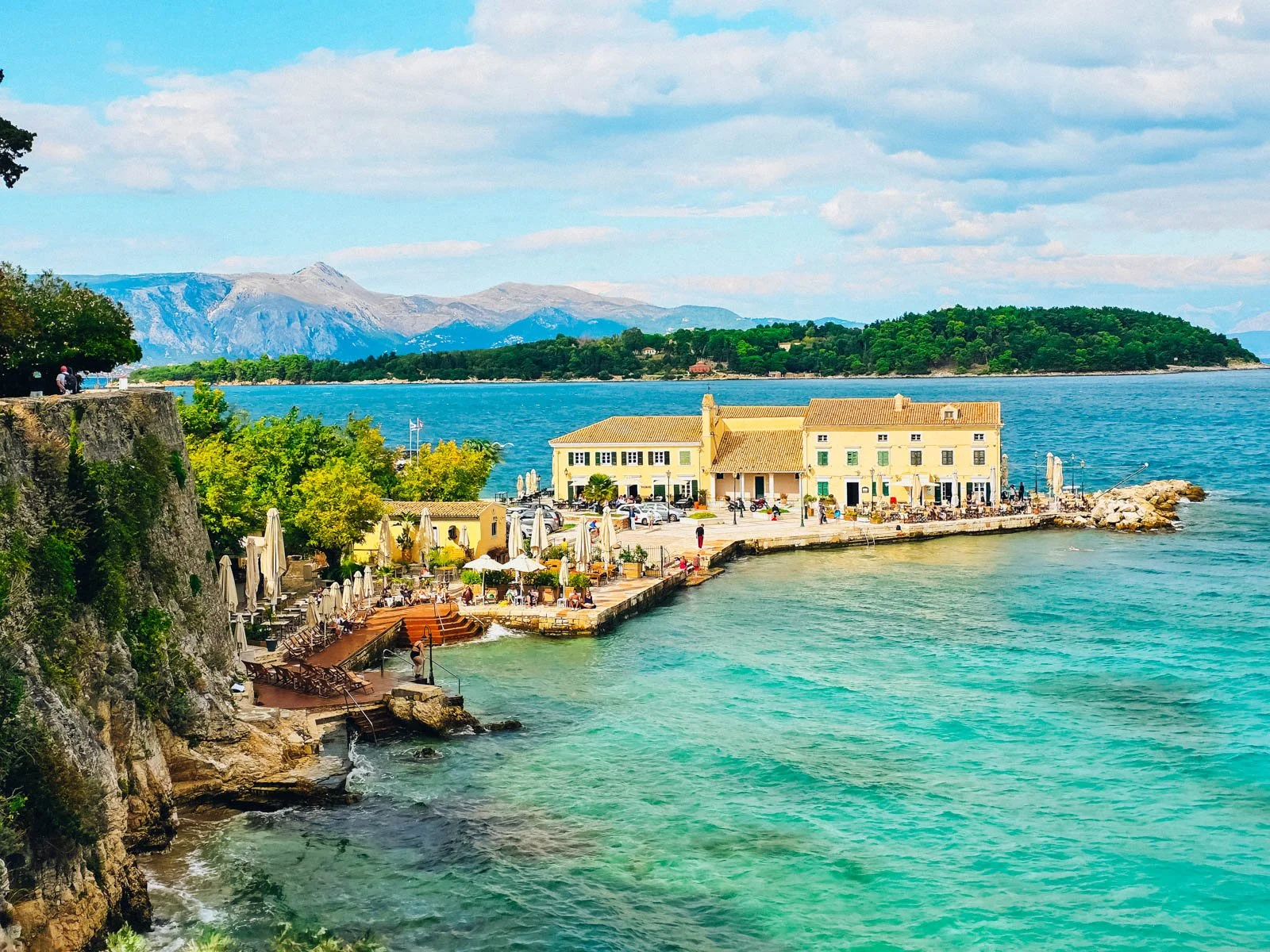 A yellow building on a concrete dock surrounded by clear blue water