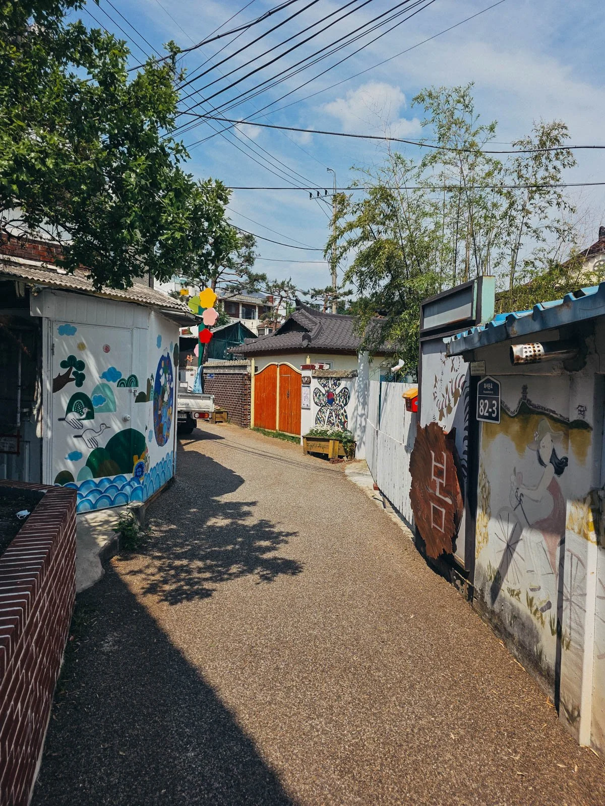 A small path lined with house walls covered in murals