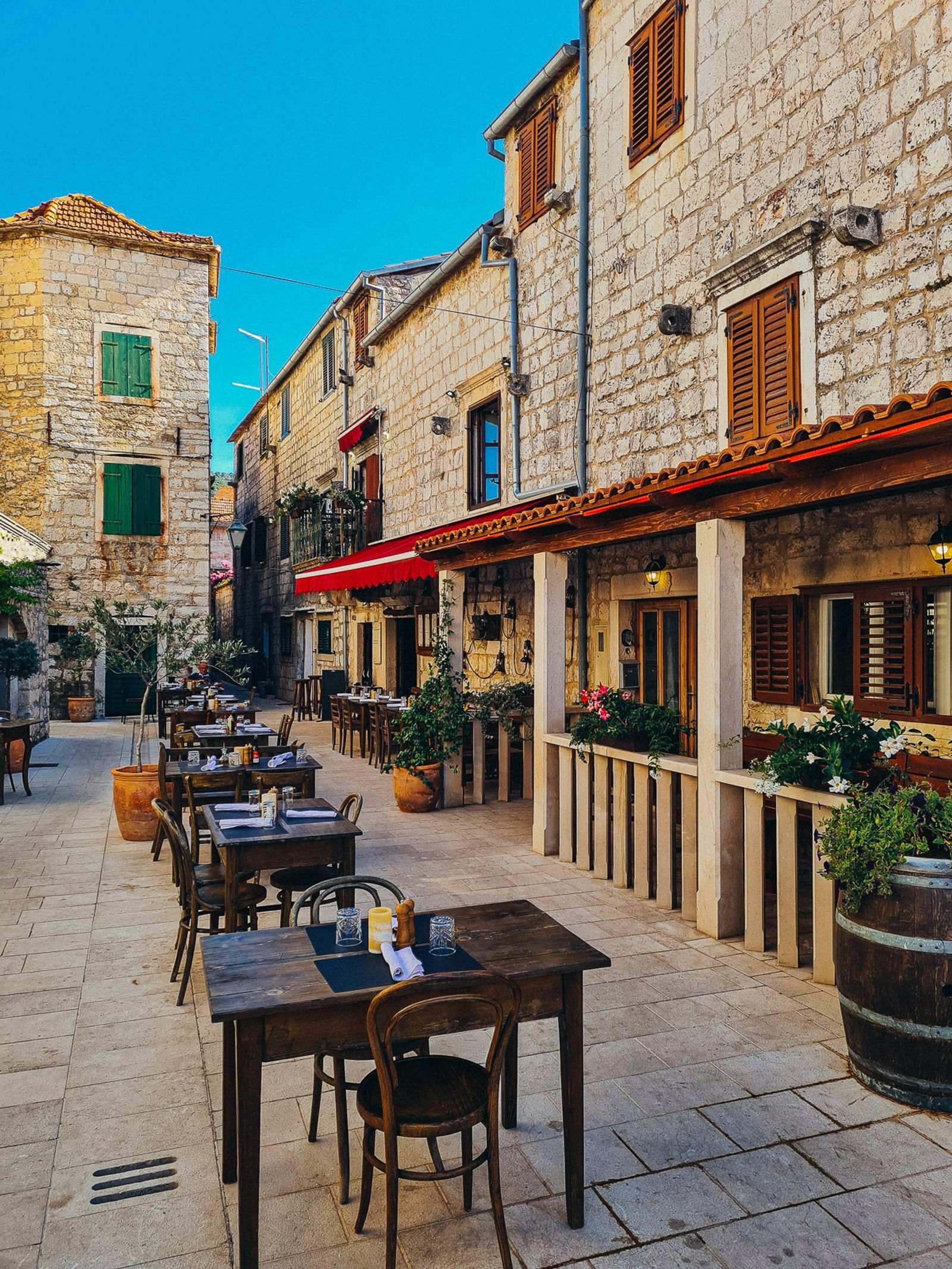 dining tables set for eating in the cobbled street in a courtyard surrounded by old stone buildings