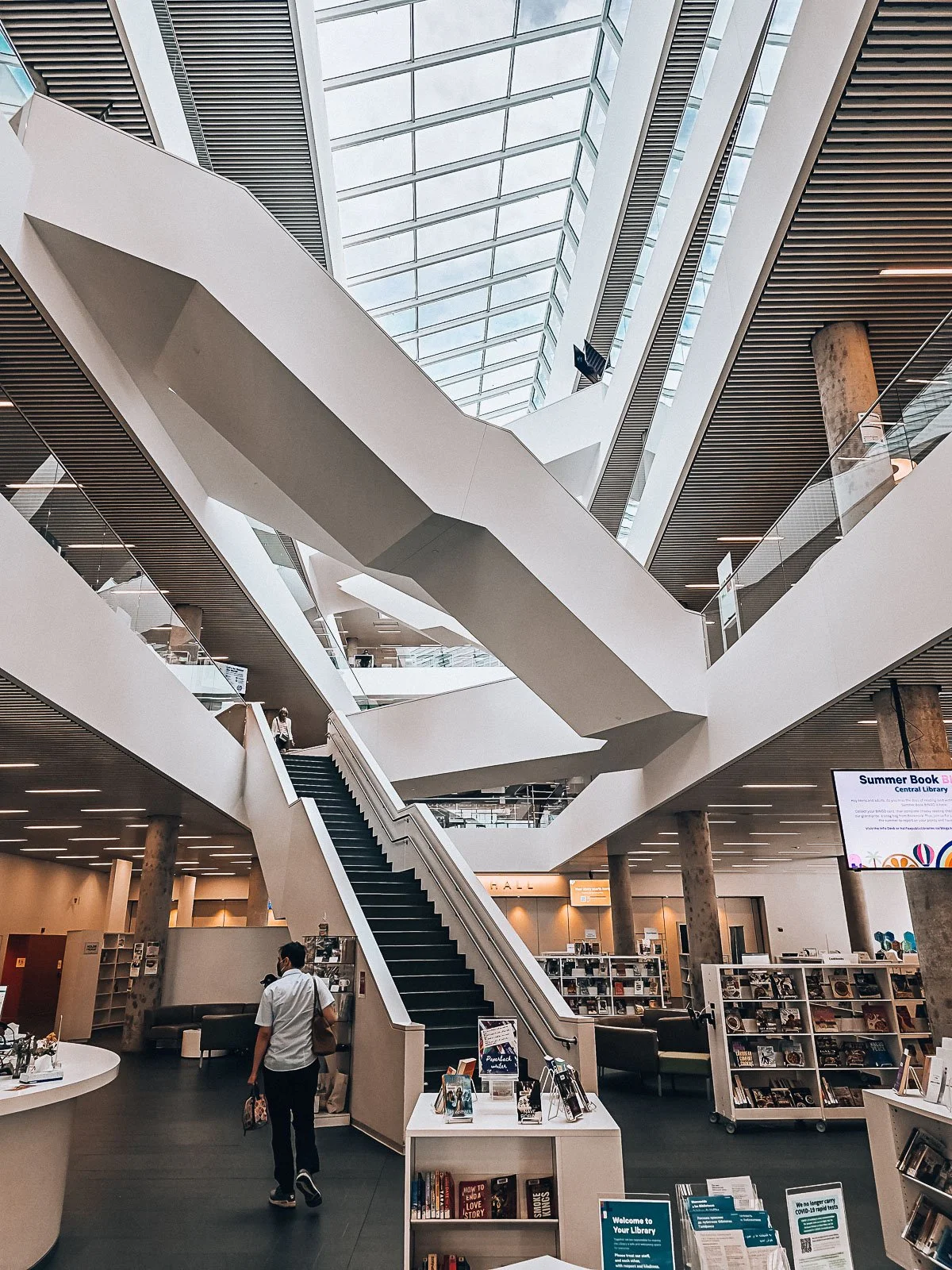 A large library with may white staircase's crisscrossing throughout the building